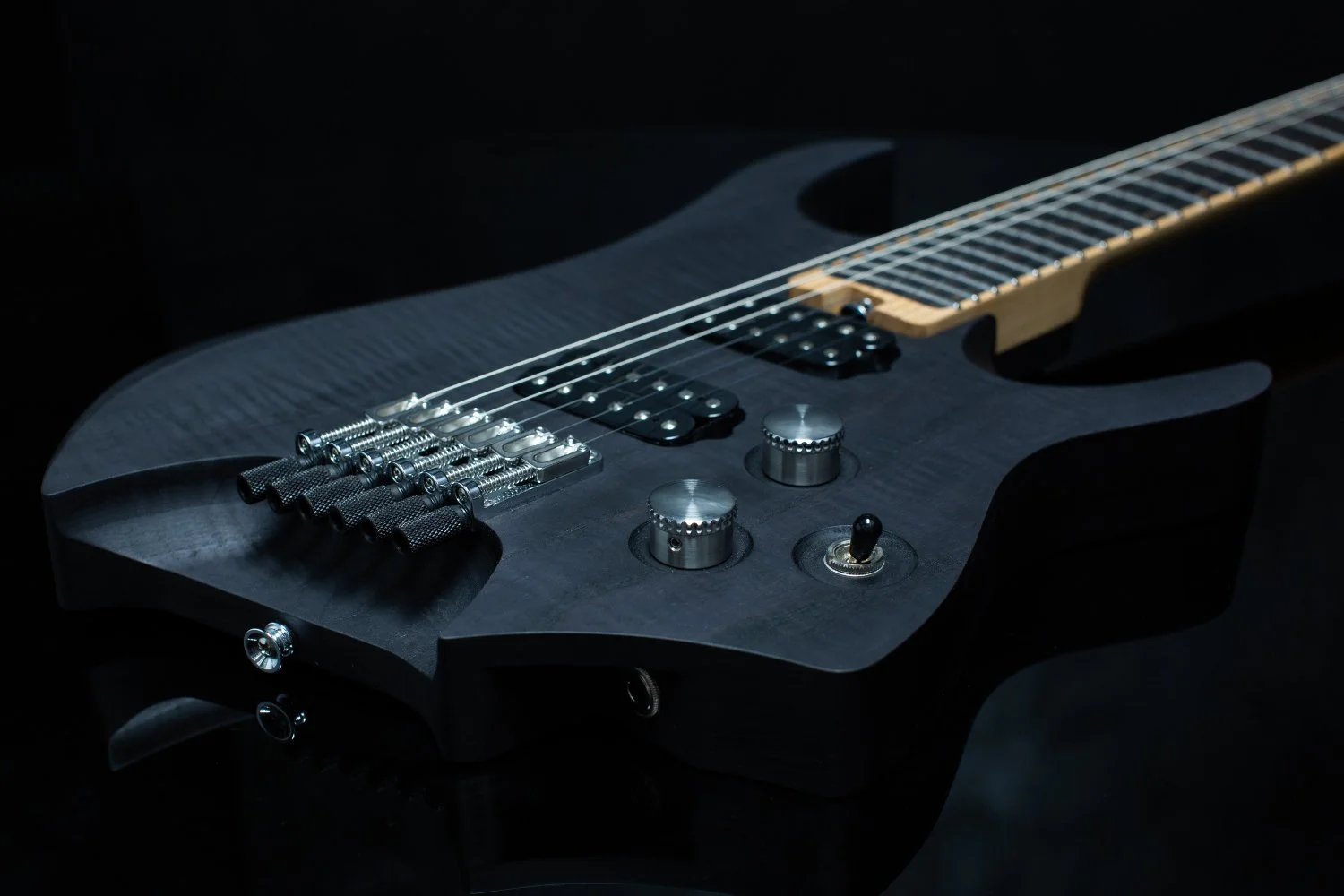 A black stained finished headless - multiscale electric guitar against a black background, featuring an inlaid fretboard and chrome hardware - 3/4 view of body
