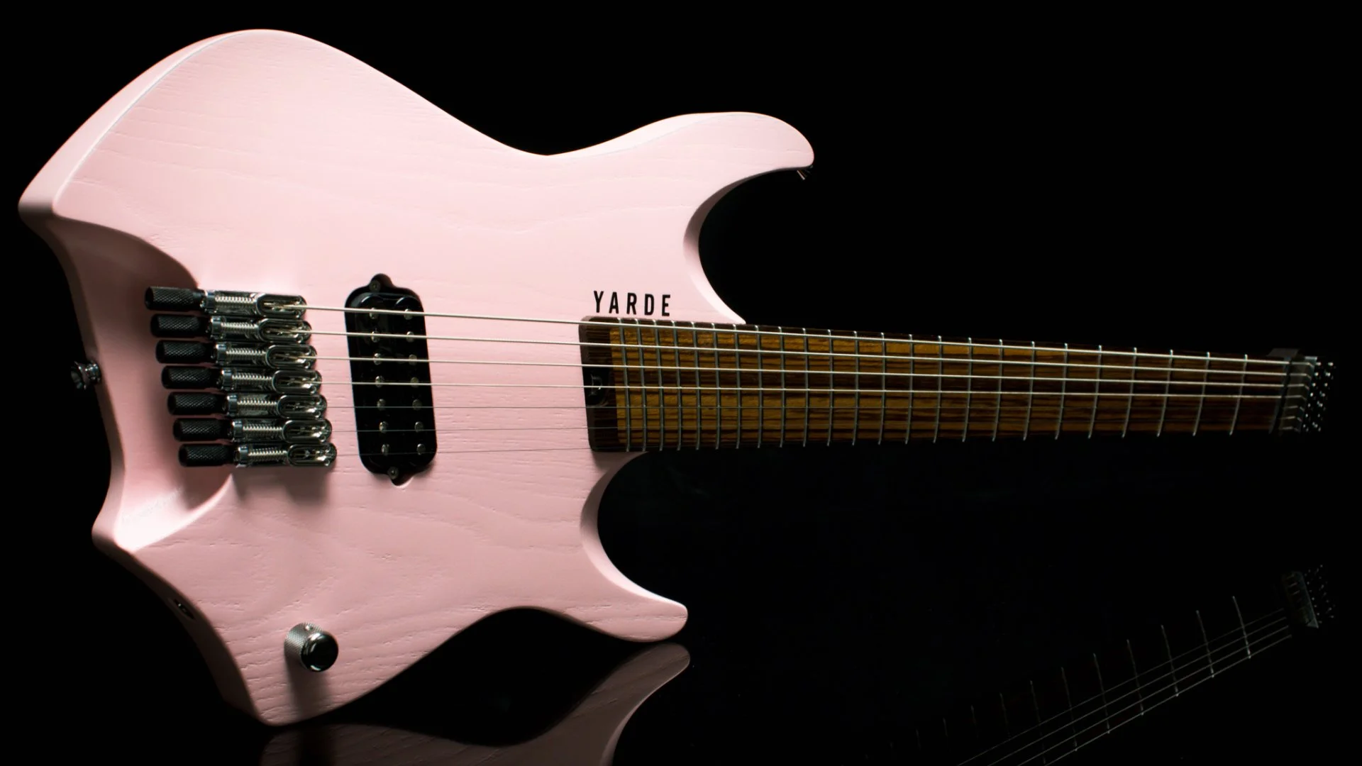 A pink 7 string headless - multiscale electric with chrome hardare and one custom humbucker pickup - landscape view