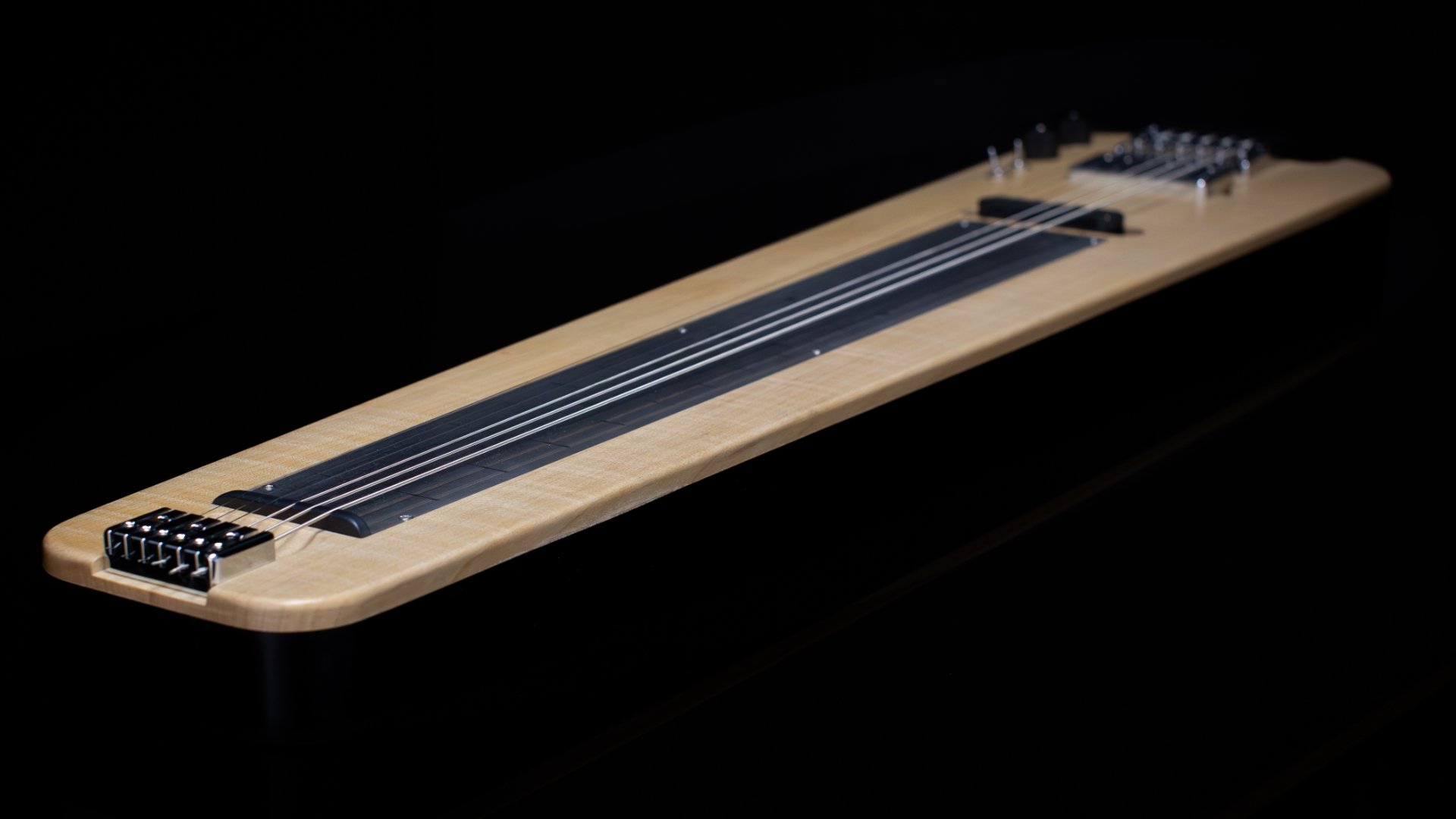 A modern headless lapsteel focussing on the flame maple cap and painted black body