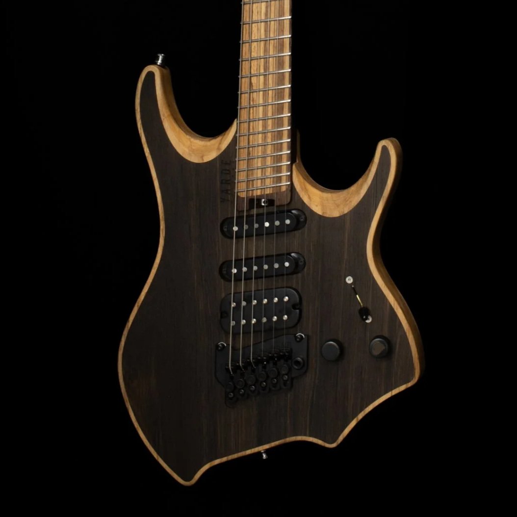 A close-up of a headless - multiscale electric guitar with an inlaid bog oak cap and HSS pickups, tremolo bridge against a black background - Body view