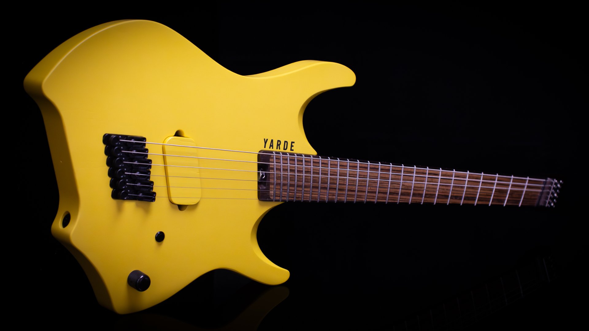 A headless - multiscale electric guitar with a bright yellow painted finish, single wooden covered humbucker pickup and a black background - Landscape view