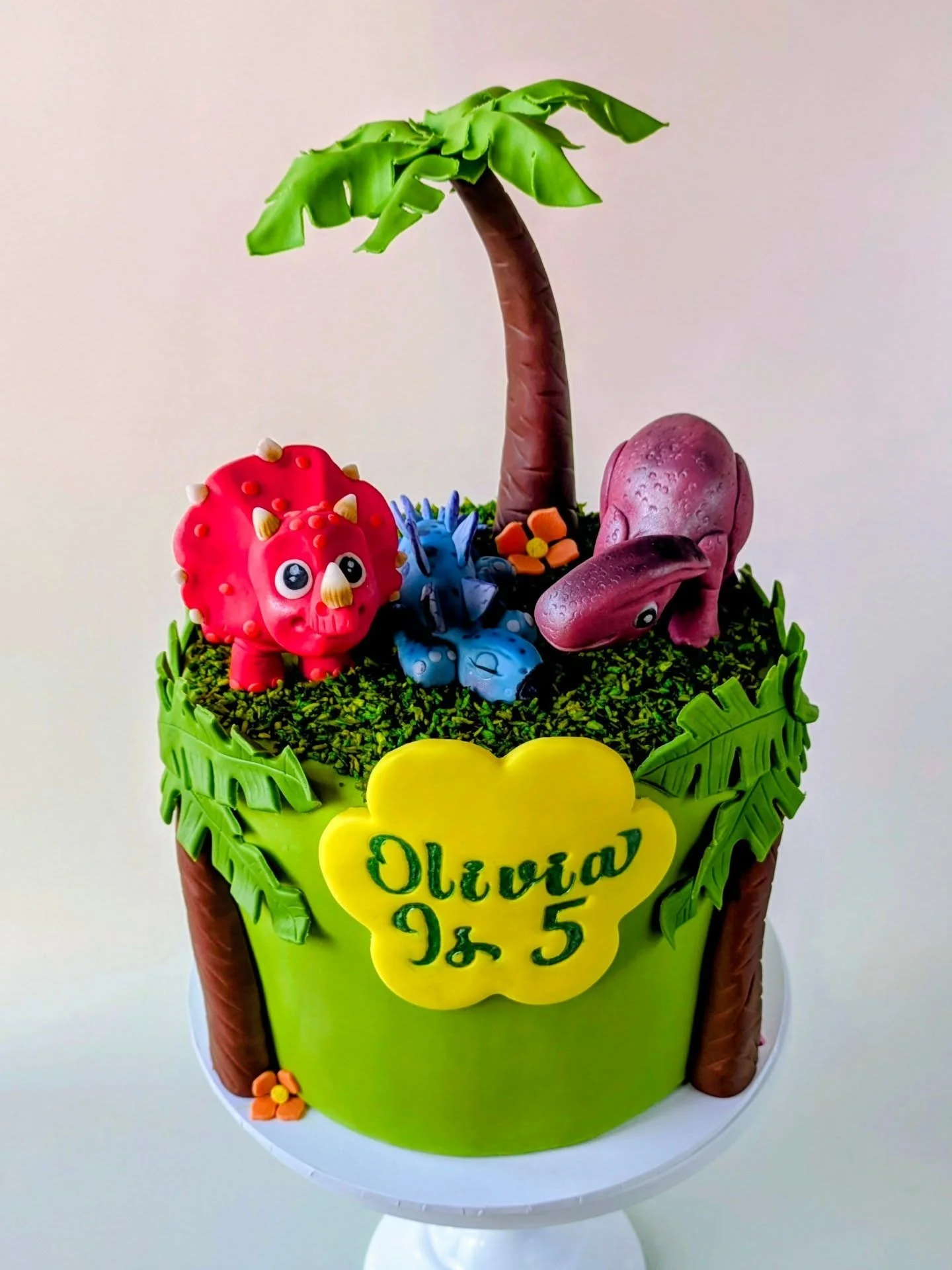 Imagine your little one's face when they walk into their birthday party and see this waiting for them.

This jungle dinosaur cake was made for Olivia's 5th birthday, complete with three handmade sugar dinosaurs, a full palm tree topper, tropical leav