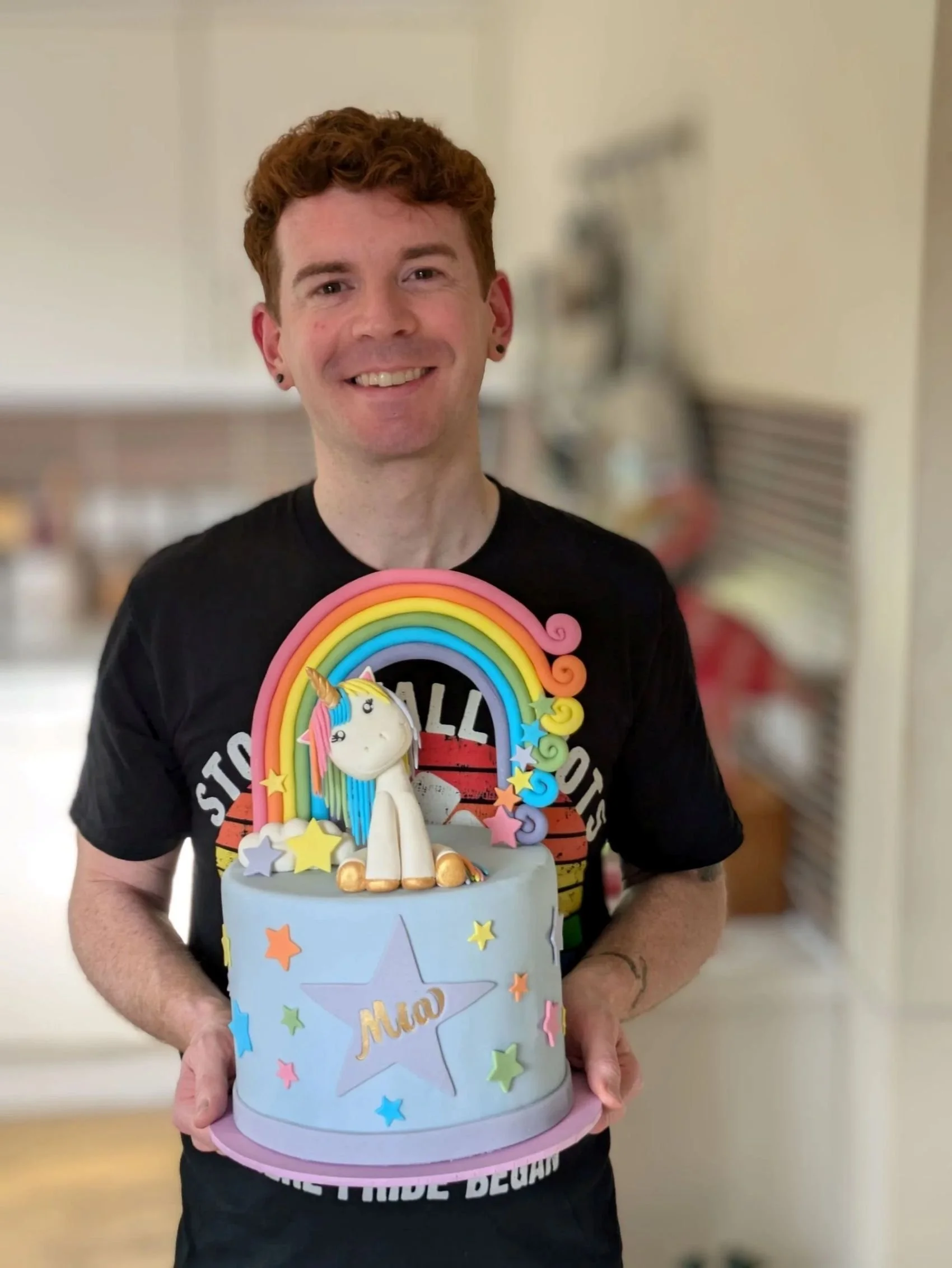 Cake Maker in Bristol holding a colourful rainbow unicorn cake