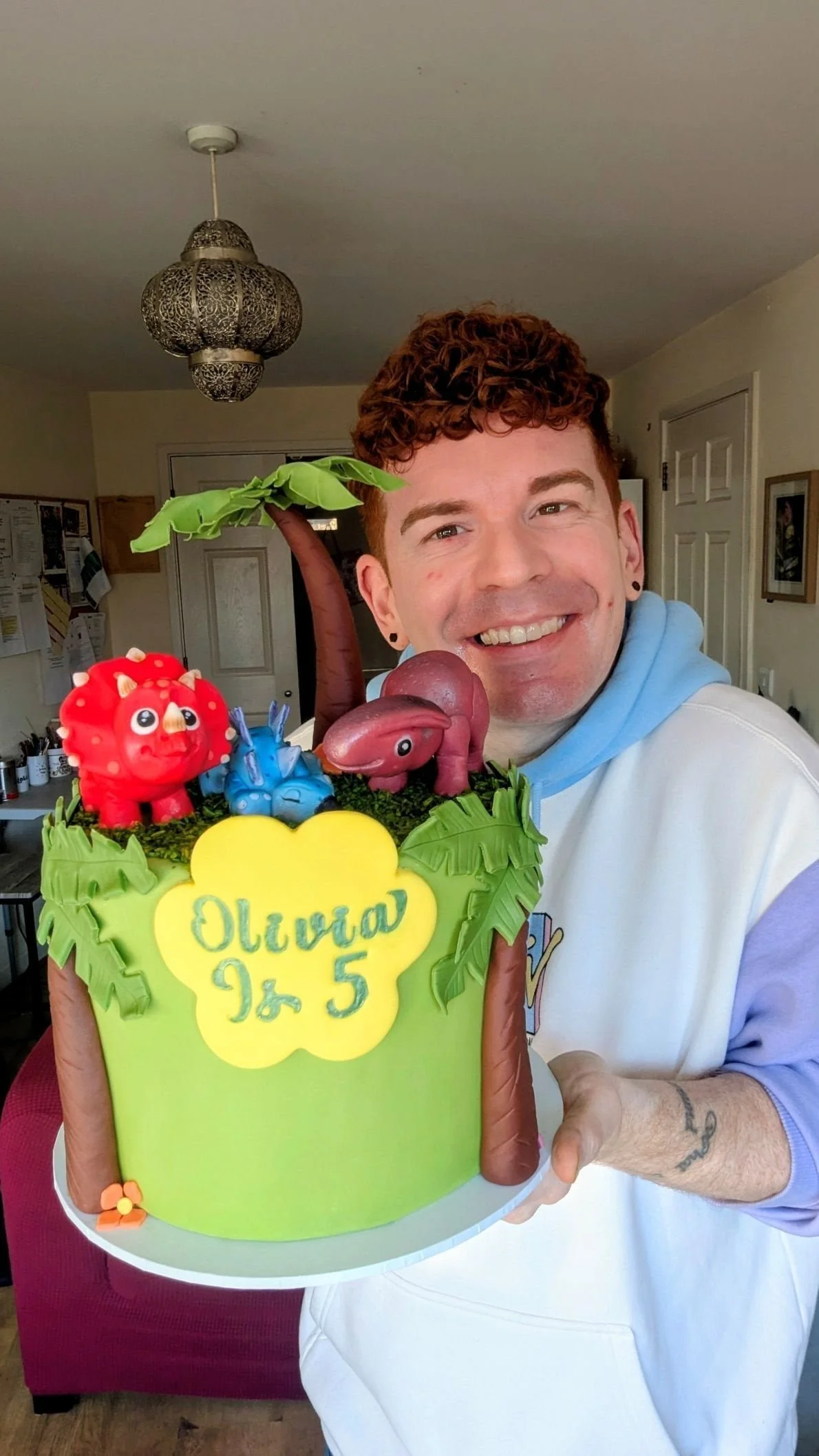 vegan cake maker in bristol holding colourful dinosaur cake