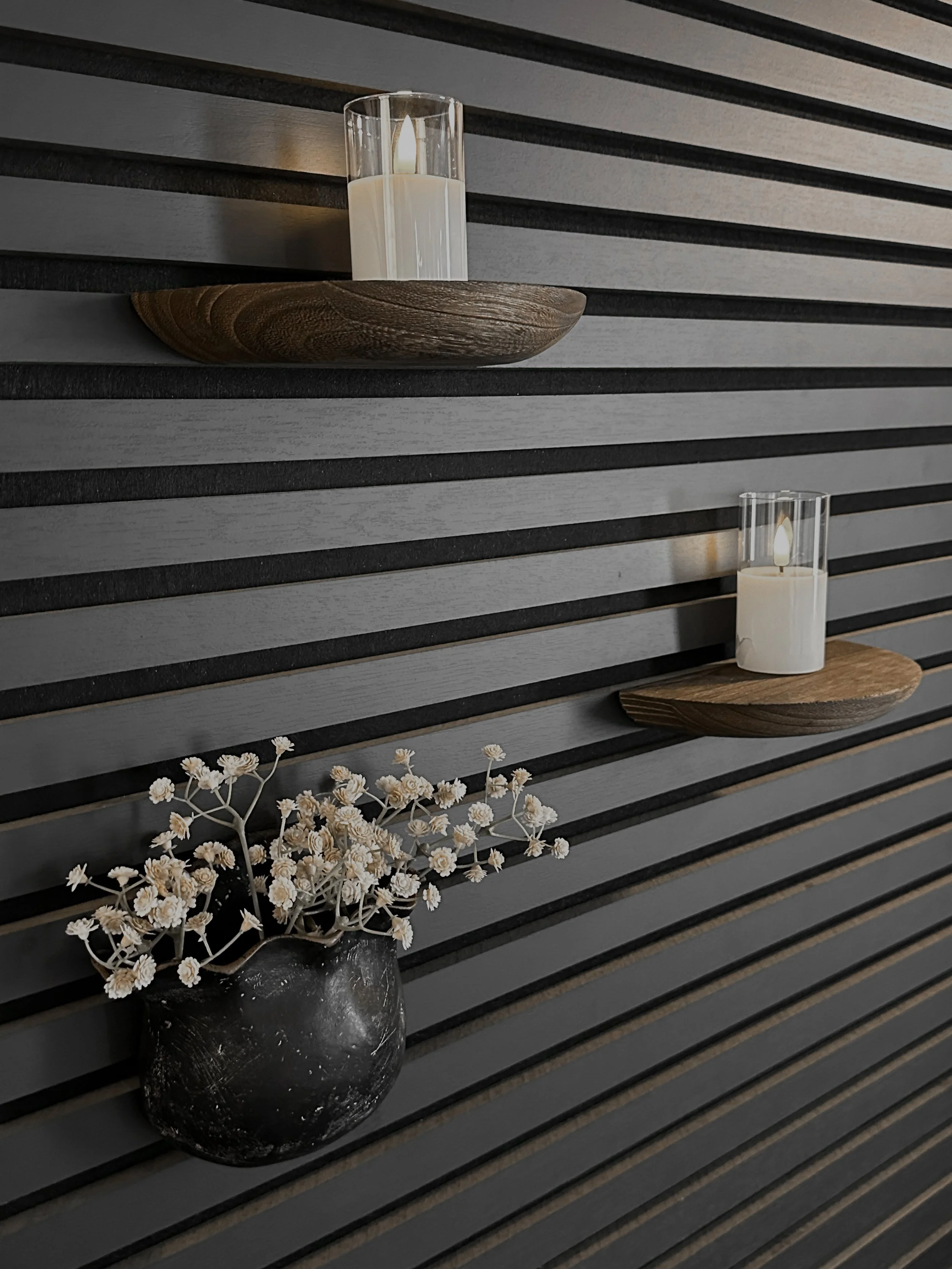 Minimal candle shelves mounted on a black slat wall inside an industrial modern photography studio in the Detroit area.
