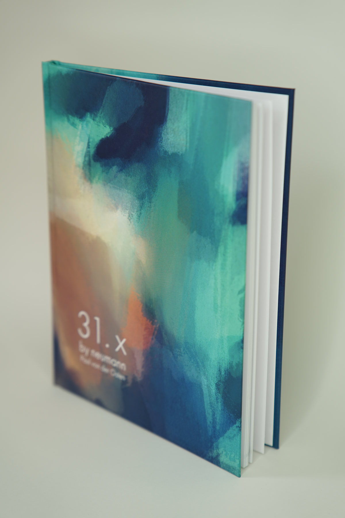 Ein offener Kunstband mit einer bunten, abstrakten Aquarellzeichnung auf dem Cover, das die Titel 31.x und by/from/en enthält.