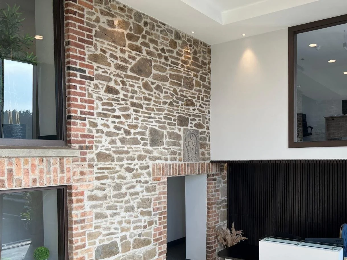 Interior wall featuring exposed brick and stone design with a modern reception area, two large windows, and decorative accents.
