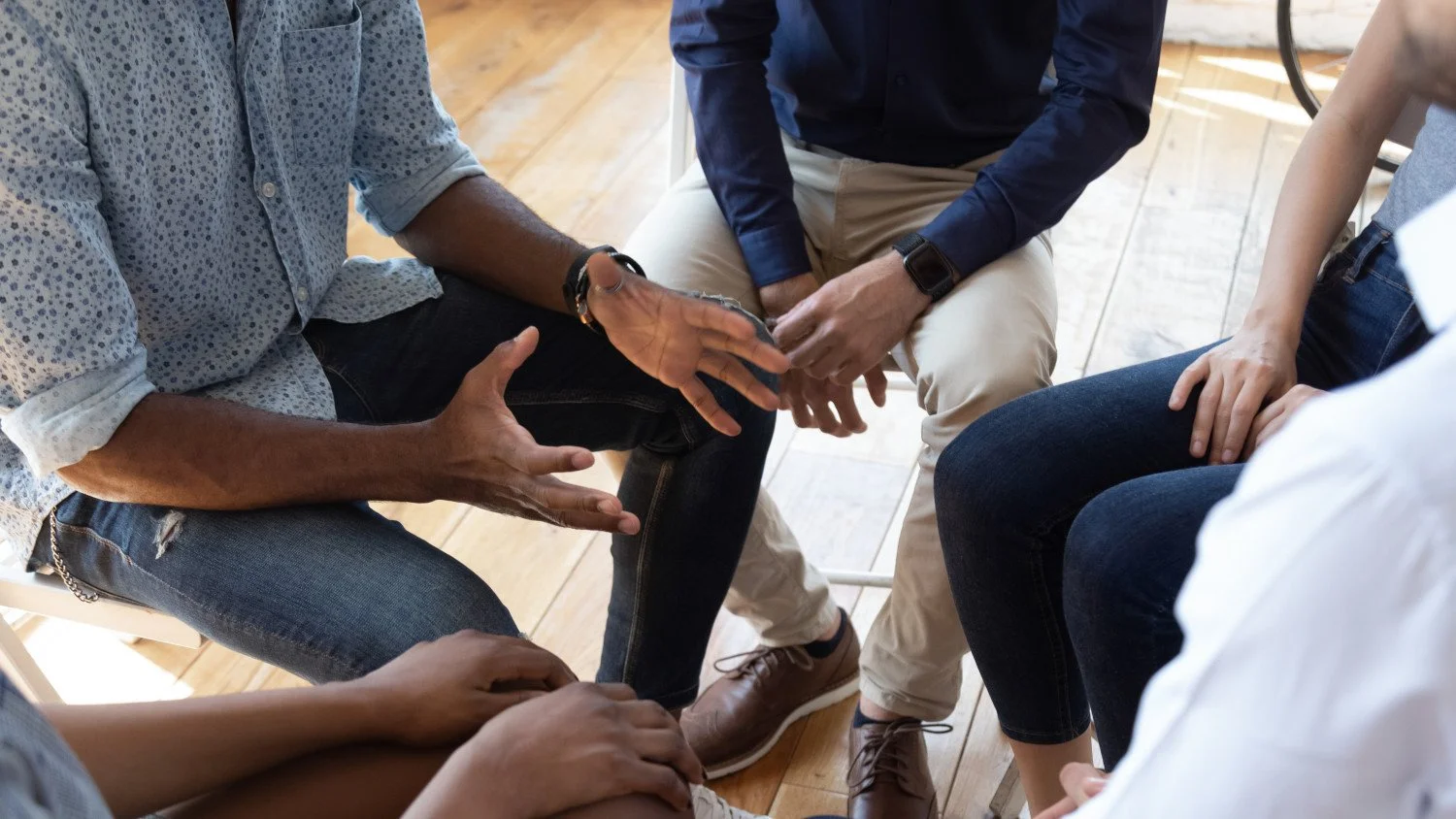 Photo of 3 people 's hands of diverse race sitting closely in a circle together