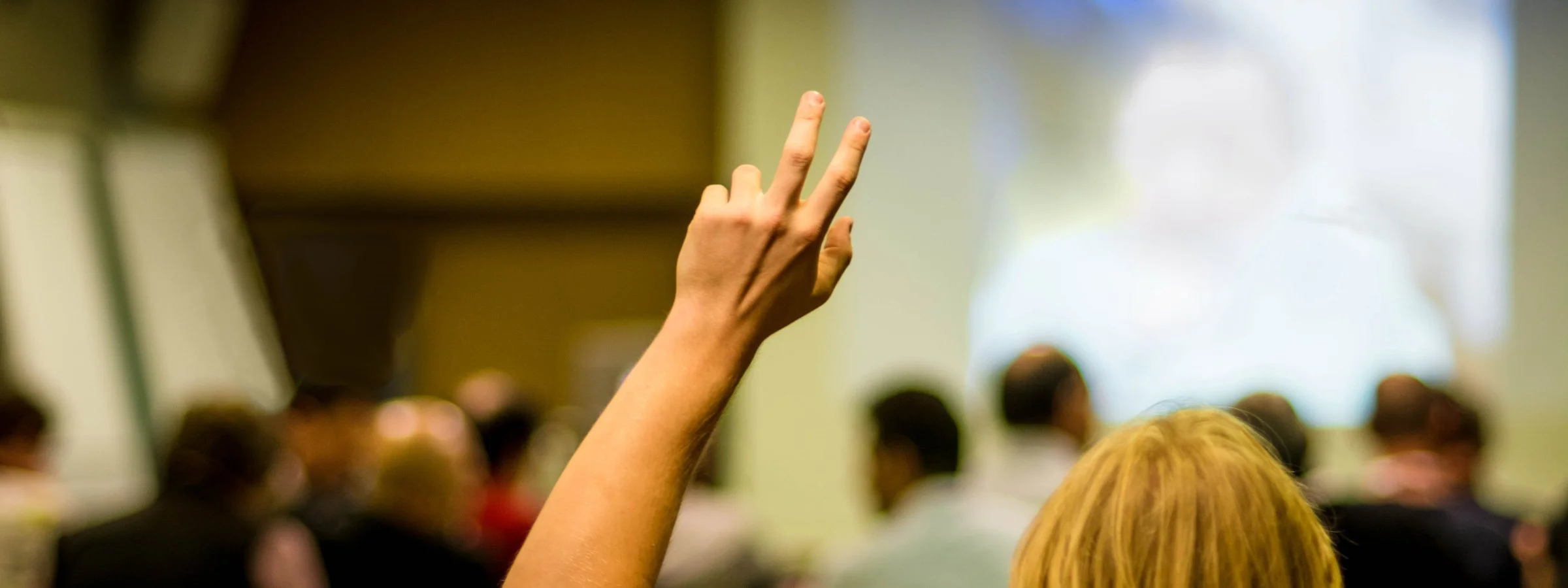 Photo of a person raising their hand to ask a question at a professional conference