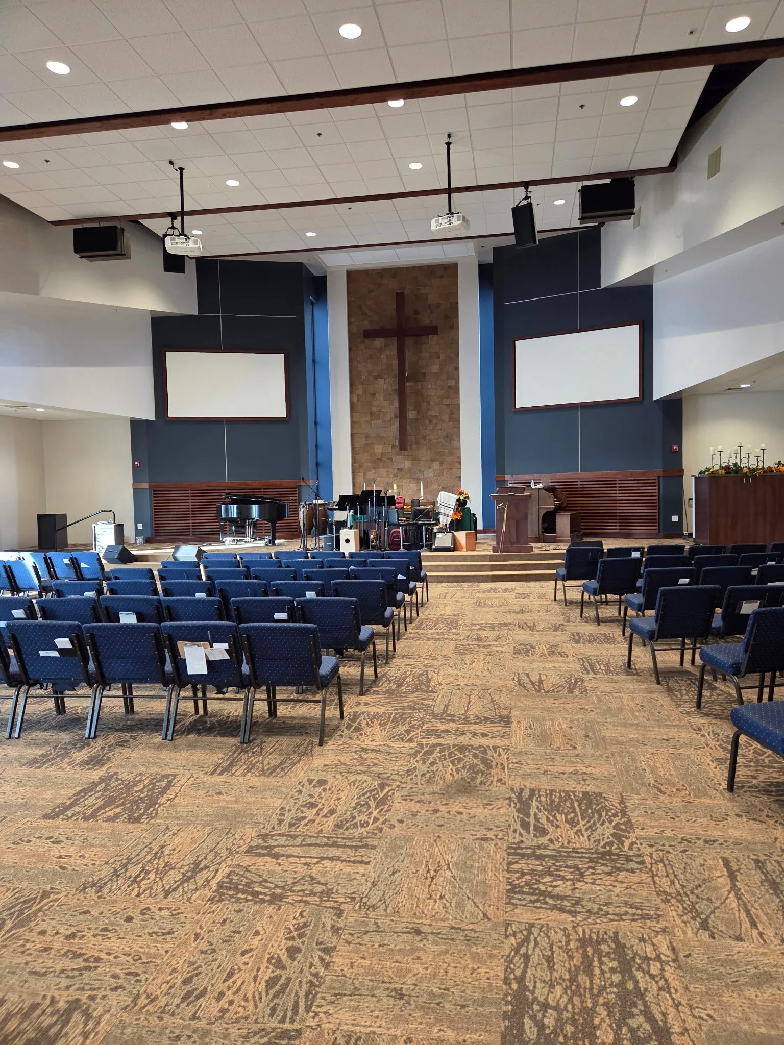 Interior of Cathedral of the Rockies Amity Campus large white walled sanctuary with dark navy accent walls rows of navy chairs and a full stage of musical instruments