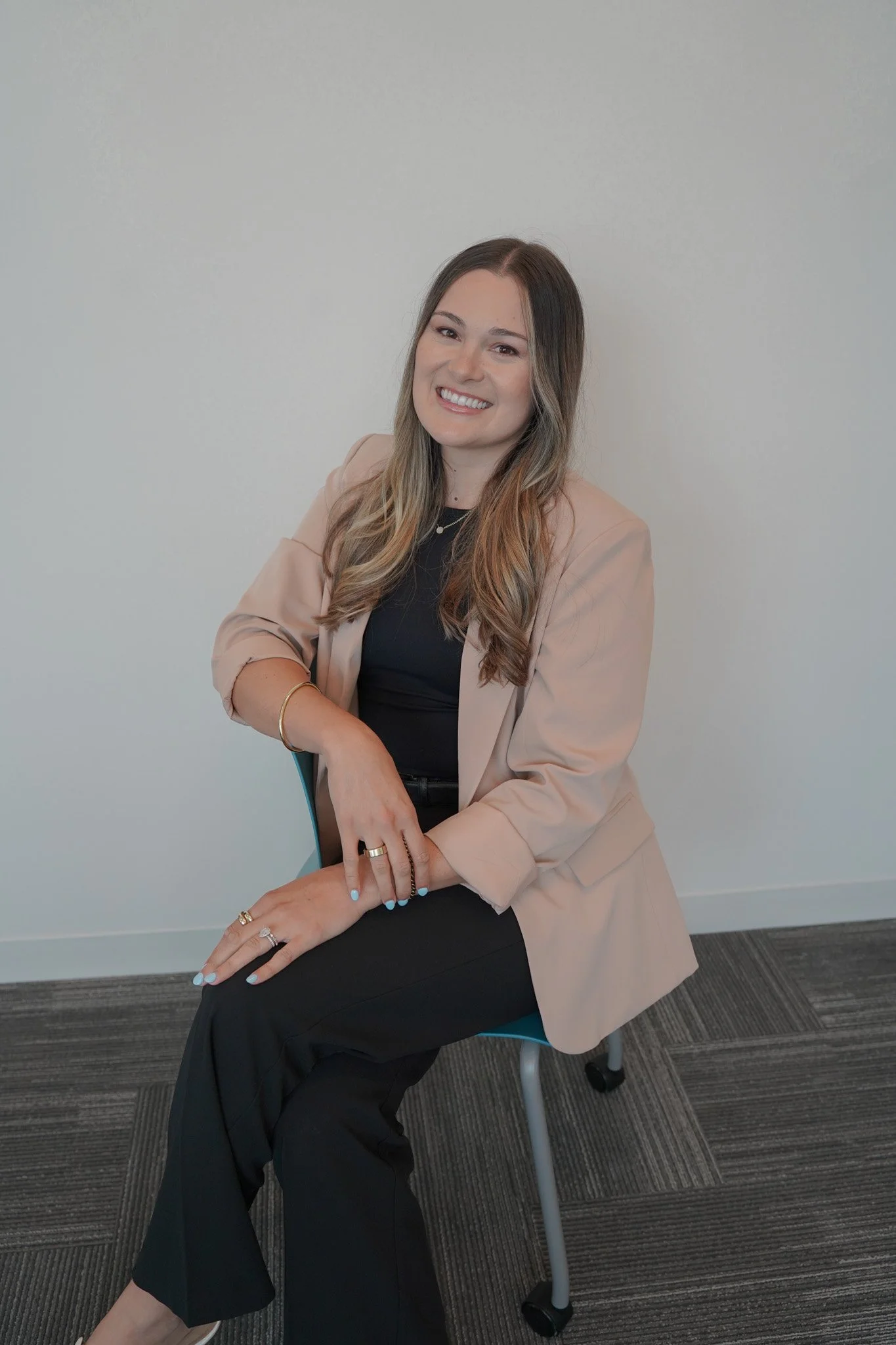 Regional Sales Manager Dana Spicer sits with her legs crossed on top of a table and wears a long red coat. 