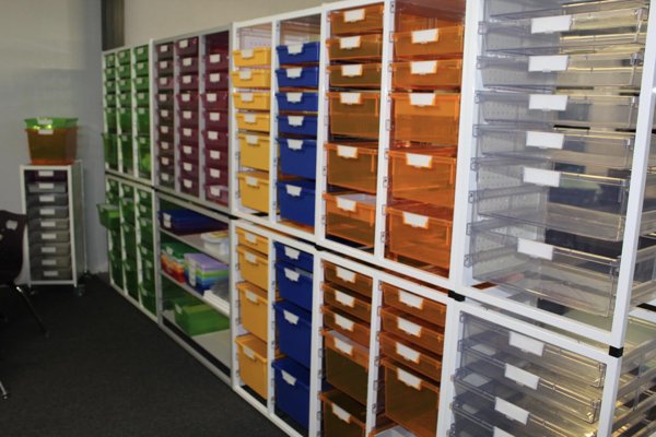 Multicolor storage bins that line a classroom wall. 