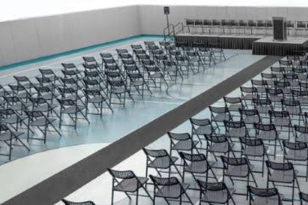 An auditorium with dozens of black folding chairs facing a main stage. 