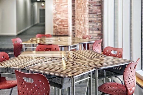 Five desks pushed together to create a star pattern. Red chairs sit next to the desks. 