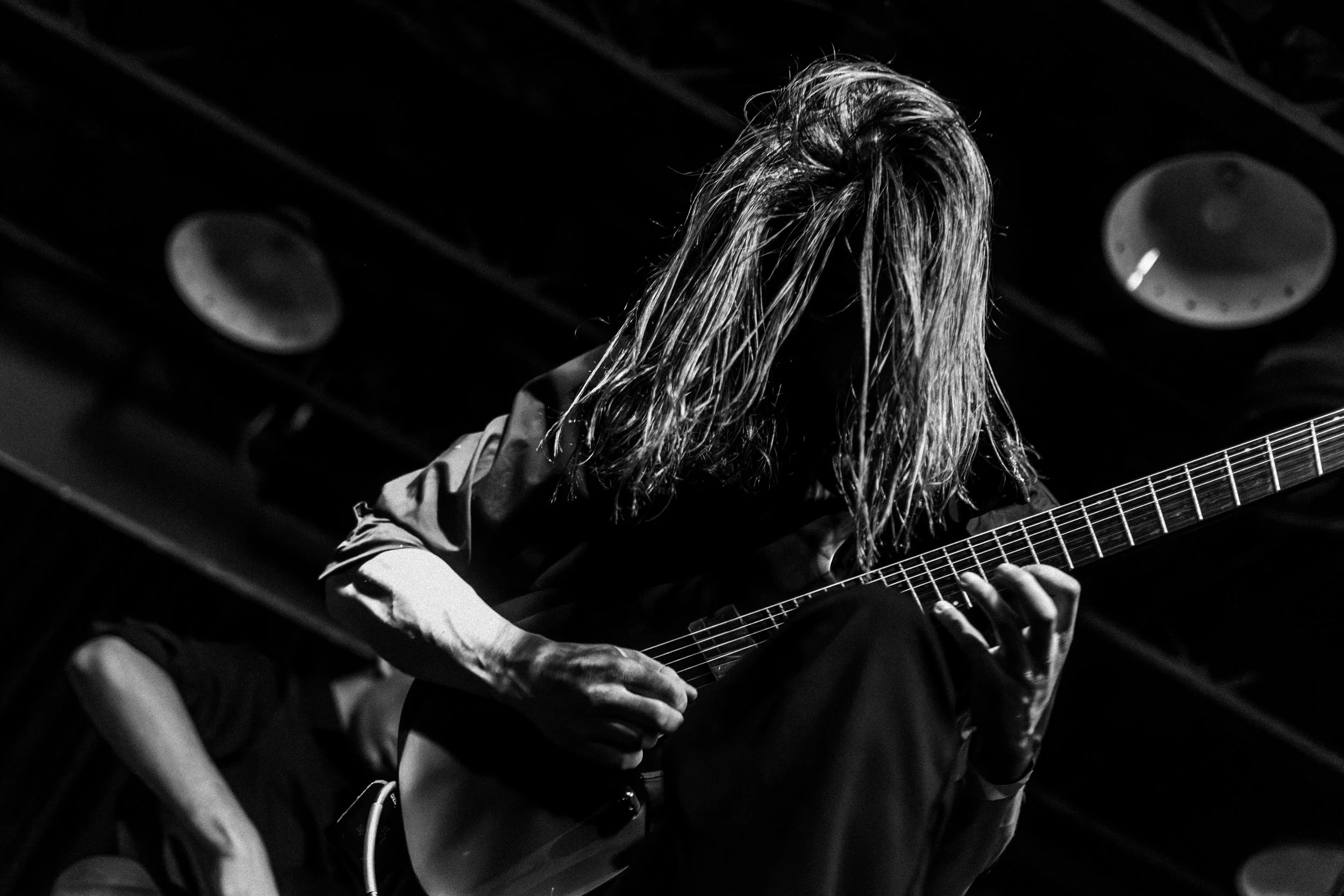 A young man plays a solo on the electric guitar with his hair in his face at the Tier Two Live Youth Battle of the Bands