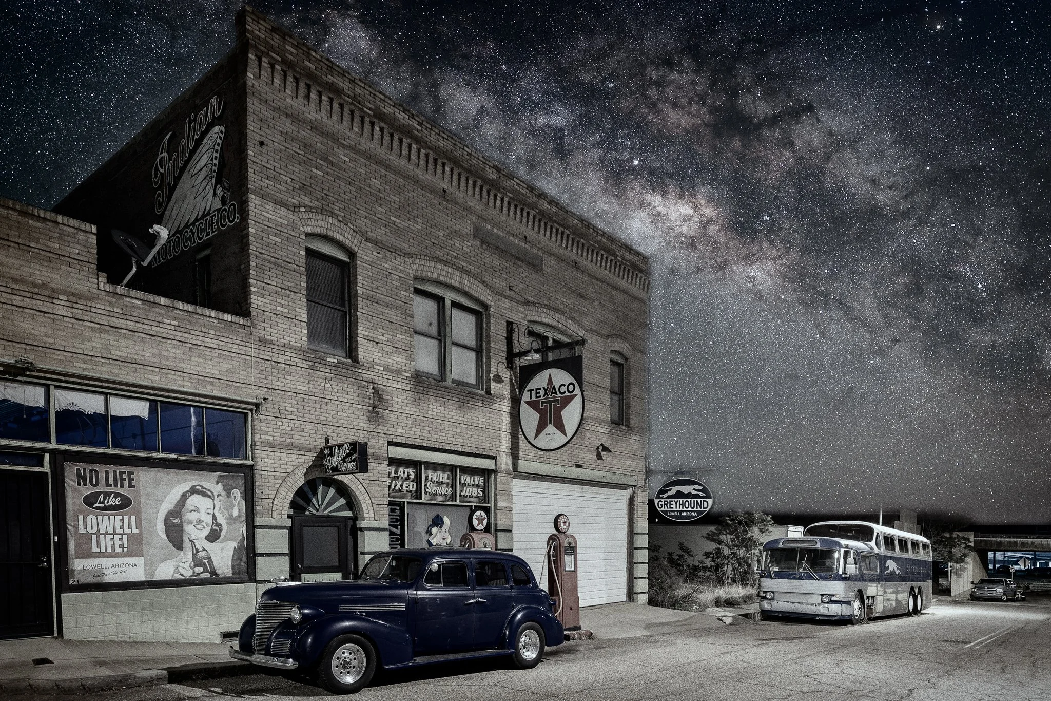 Erie Street bus depot and Texaco station with vintage Greyhound bus and classic car under starry night sky in Lowell, Arizona