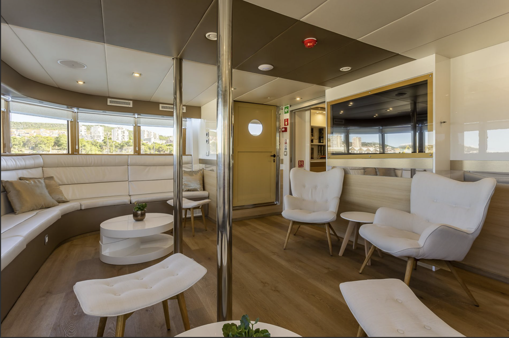 Yacht indoor lounge with white armchairs and a bar