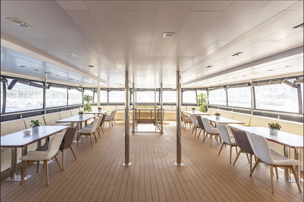 Yacht dining salon with tables set beside panoramic windows