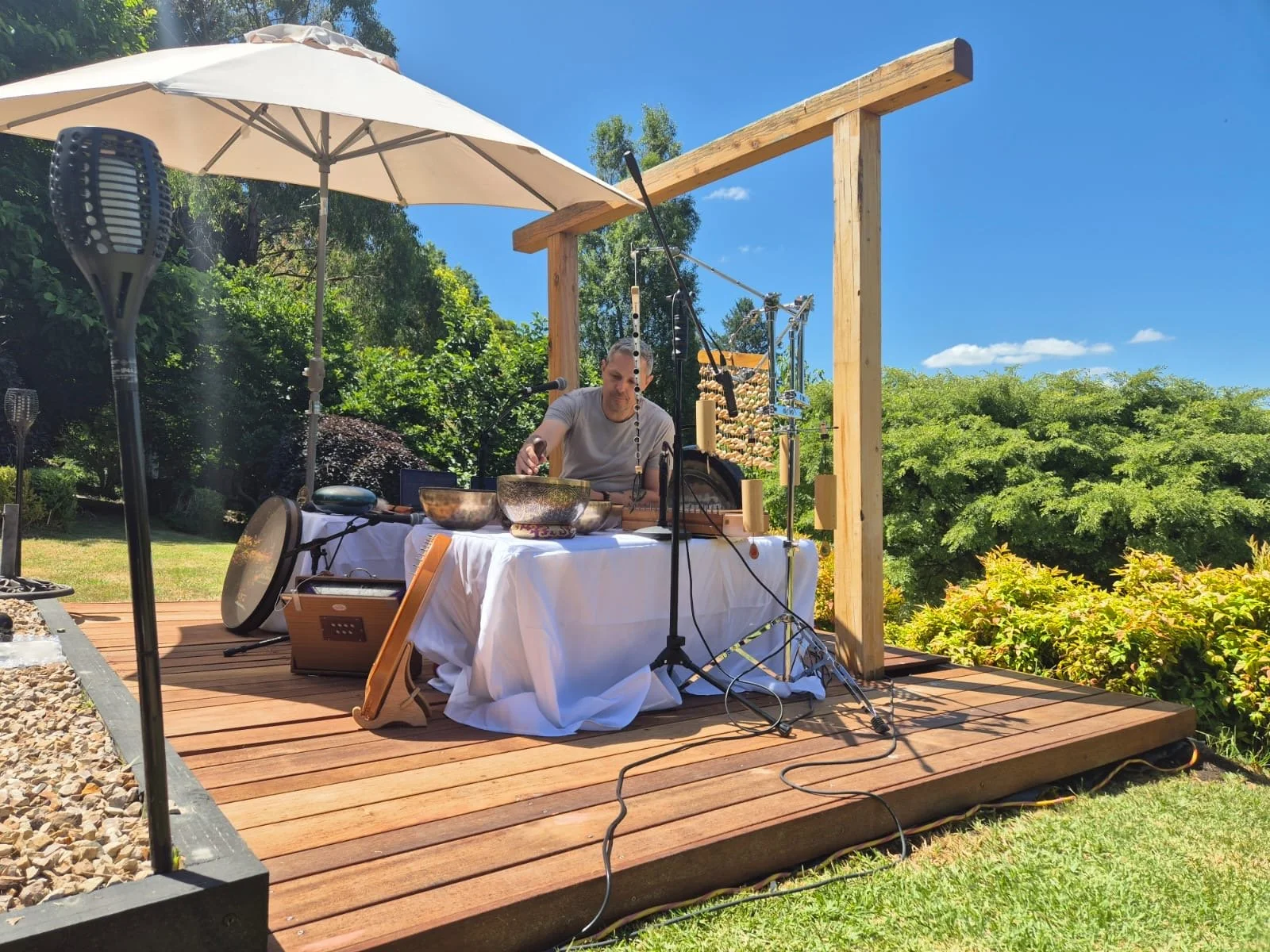 Outdoor sound healing setup for a wellness retreat near Melbourne — singing bowls and chimes on a garden deck