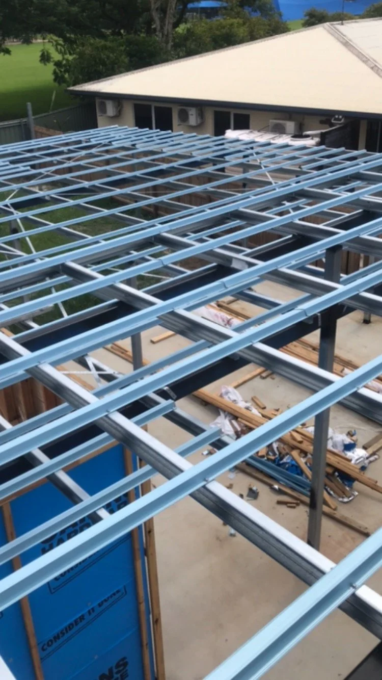 Construction site with steel roof framework and building materials.
