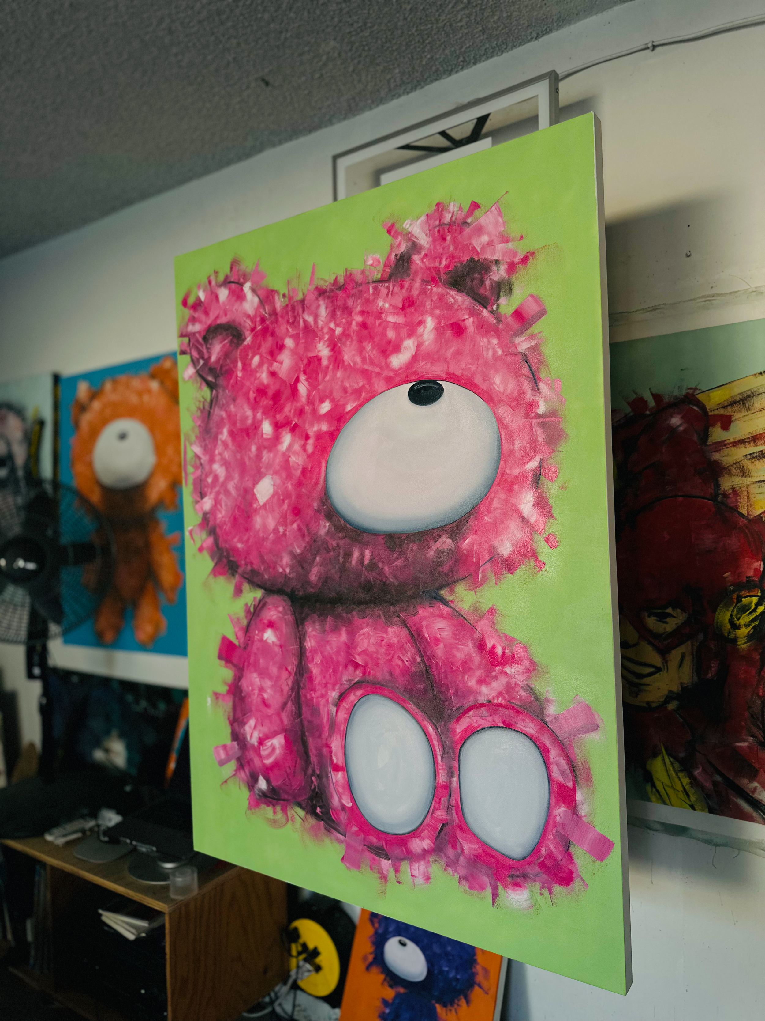 Painting of a pink teddy bear with a round white face and black nose on a green background.