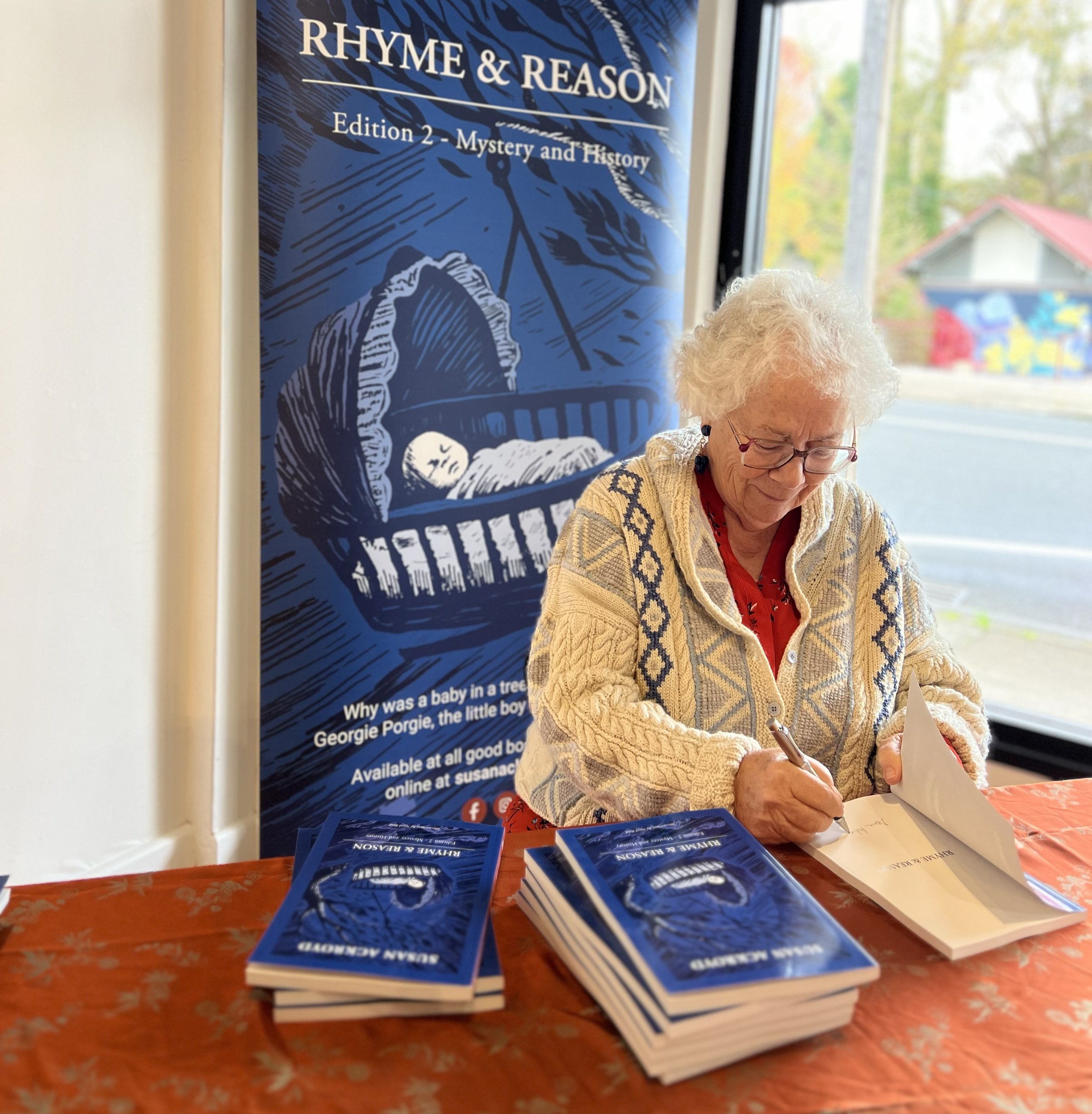 Susan Ackroyd signing copies of Rhyme & Reason at a book event.