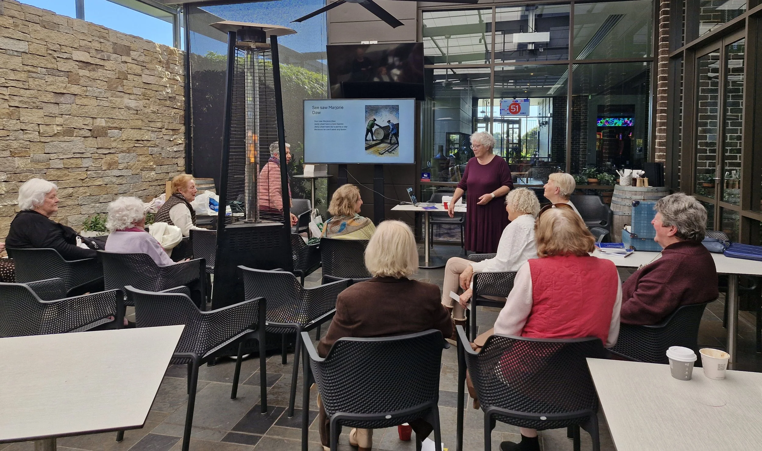 Susan Ackroyd presenting an illustrated talk about the history of nursery rhymes to a community audience.