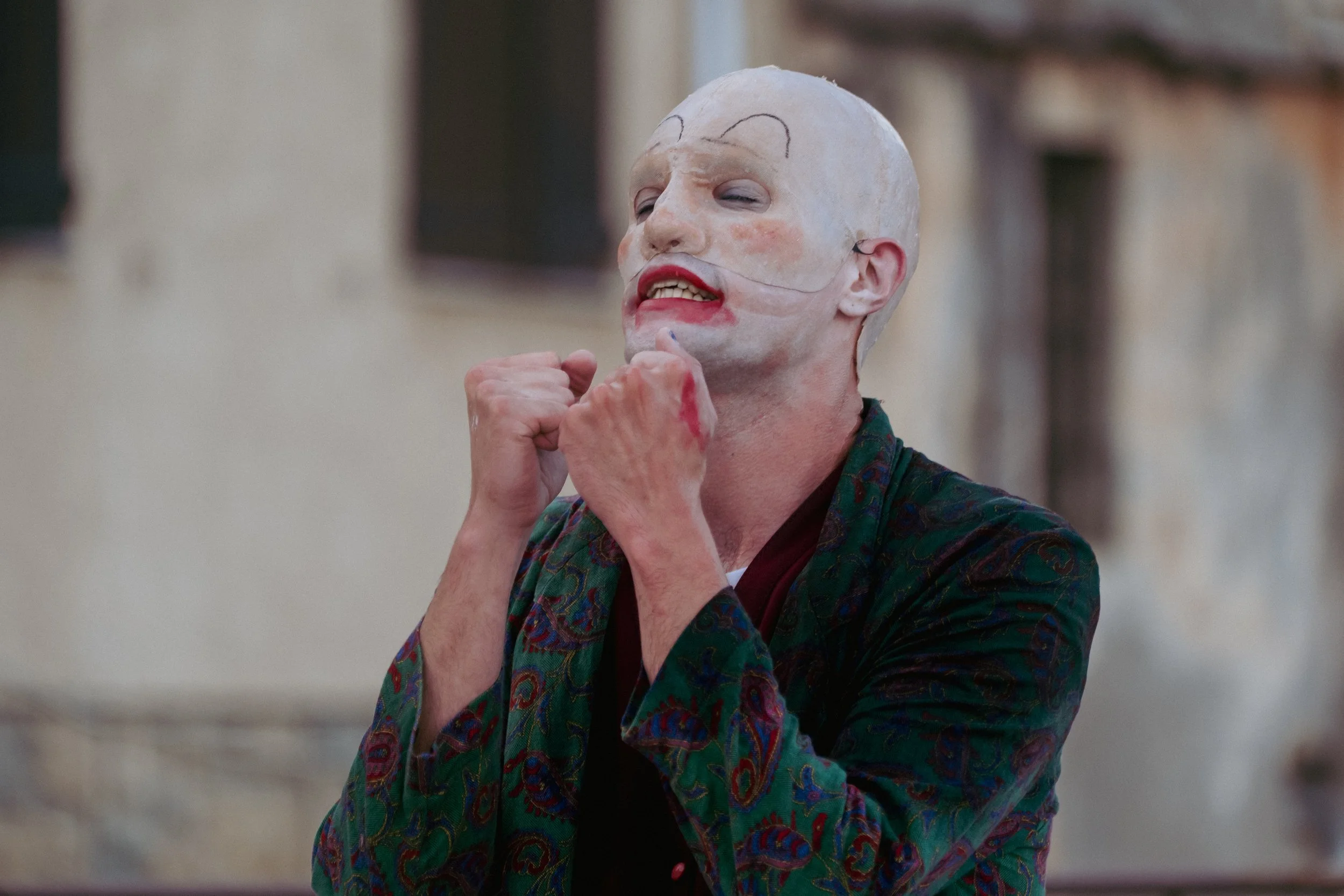 Une personne portant un maquillage de clown, avec un visage pâle, des lèvres rouges, et un maquillage dessiné en haut du front. . Extrait de Service Partiel.