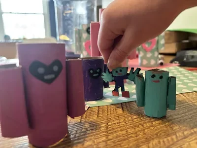 A family of cardboard tube robots on a table.