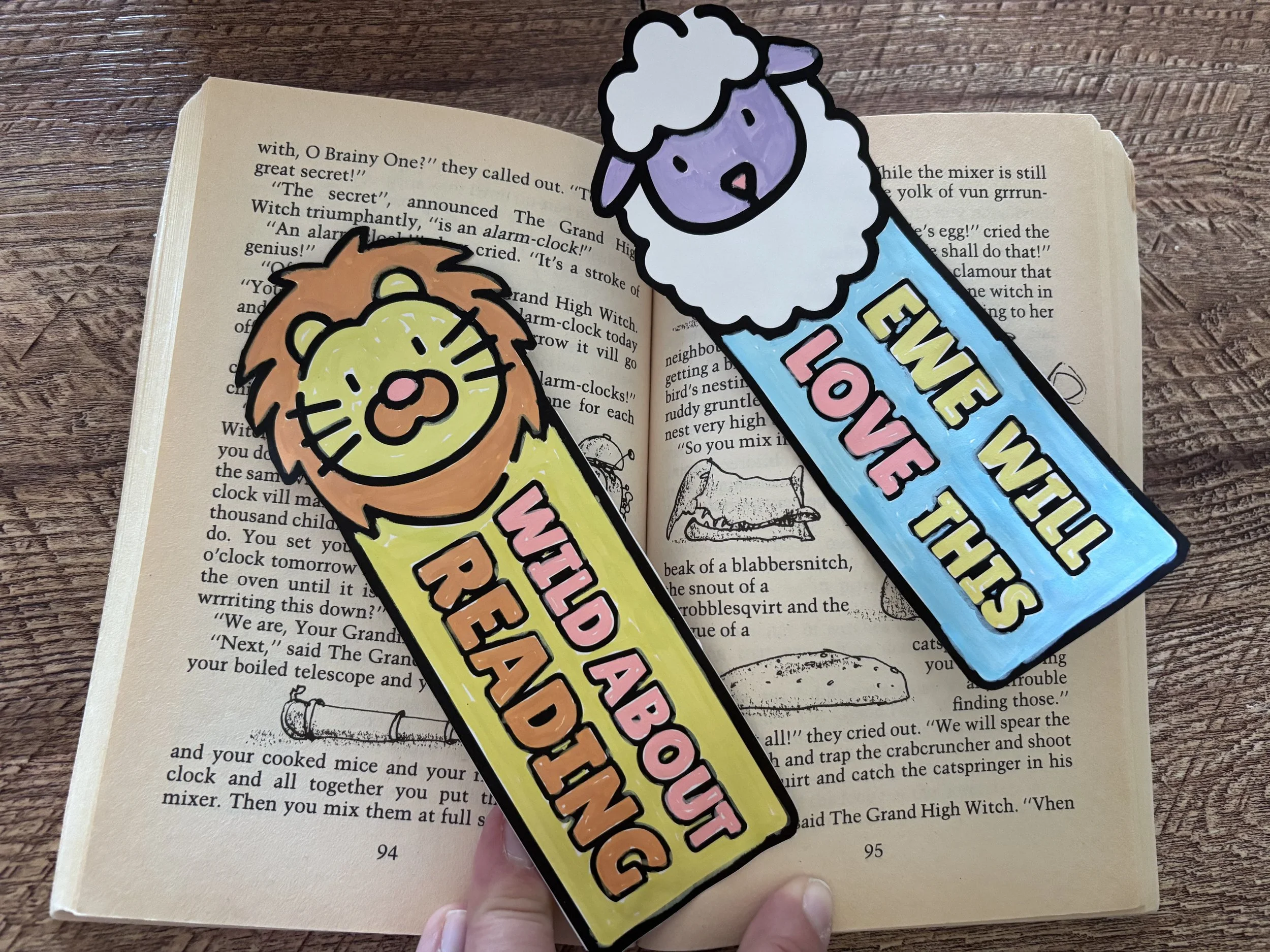 Two bookmarks that say "Wild about Reading" and "Ewe will love this" with a lion and lamb sitting on top of a book