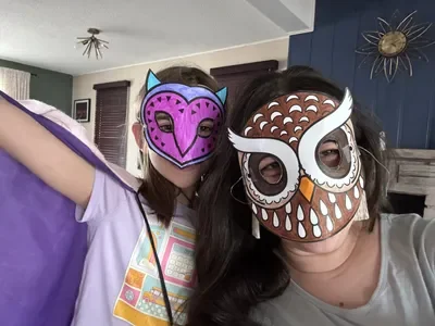 A mother and daughter wearing the owl masks they colored from GlueStick