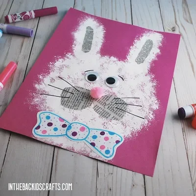 A painted rabbit with upcycled newspaper details and googly eyes on a pink background