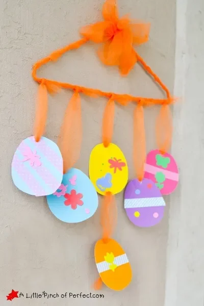 Six paper Easter eggs decorated with washi tape hang from a mobile