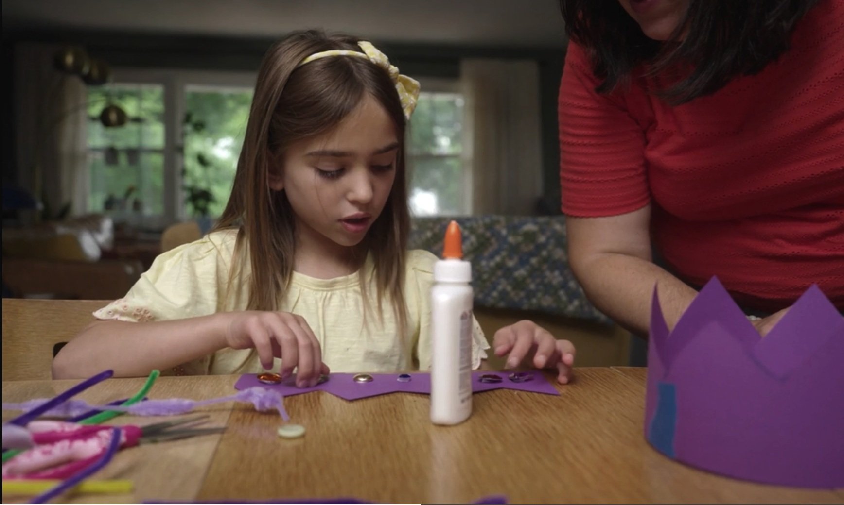 A child making crowns with construction paper, glue, and pipecleaners.