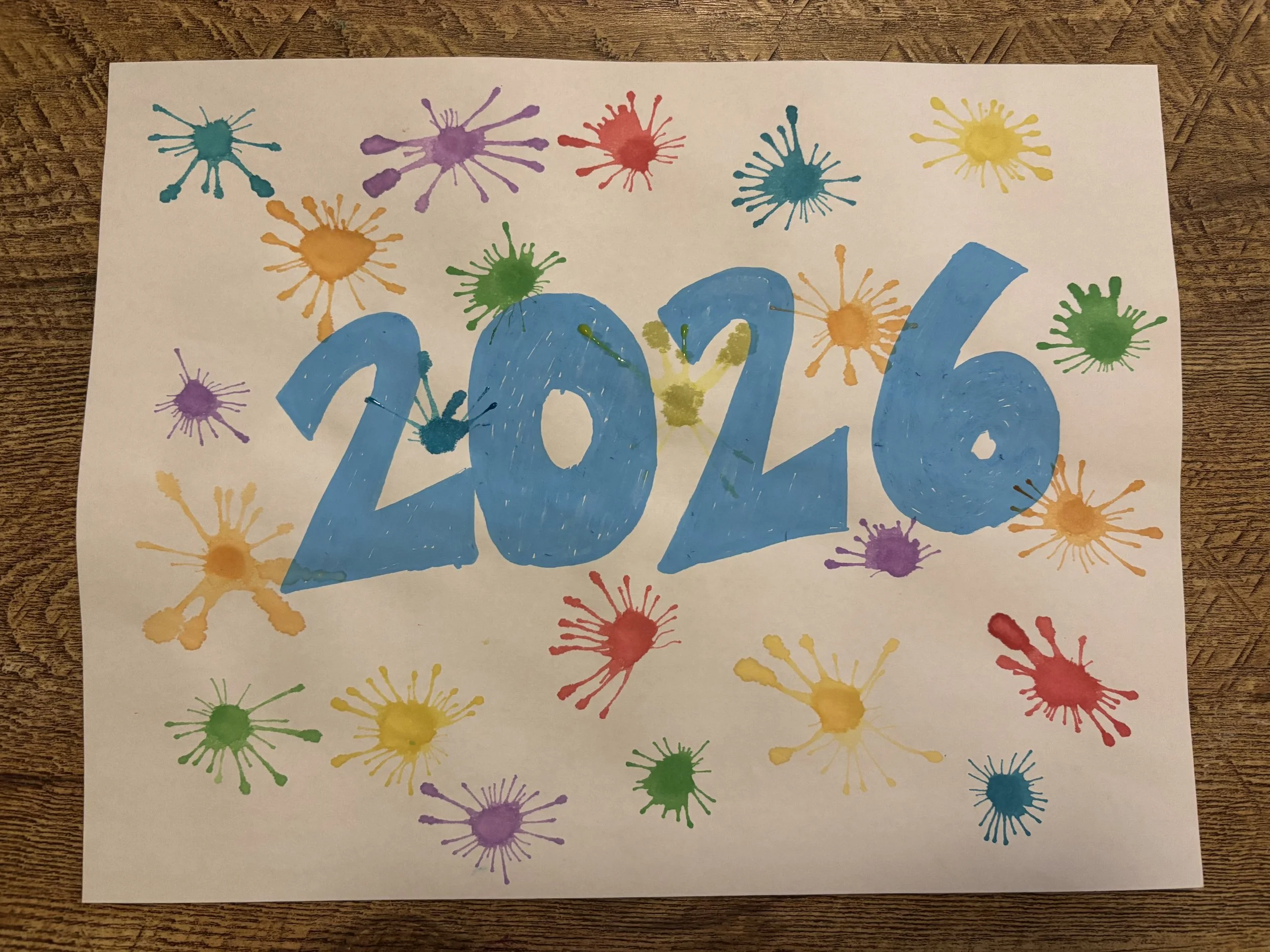 The year 2026 surrounded by water color fireworks made by blowing a paint splatter with a straw