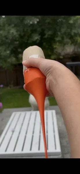 A balloon launcher about to launch a pom pom in a backyard
