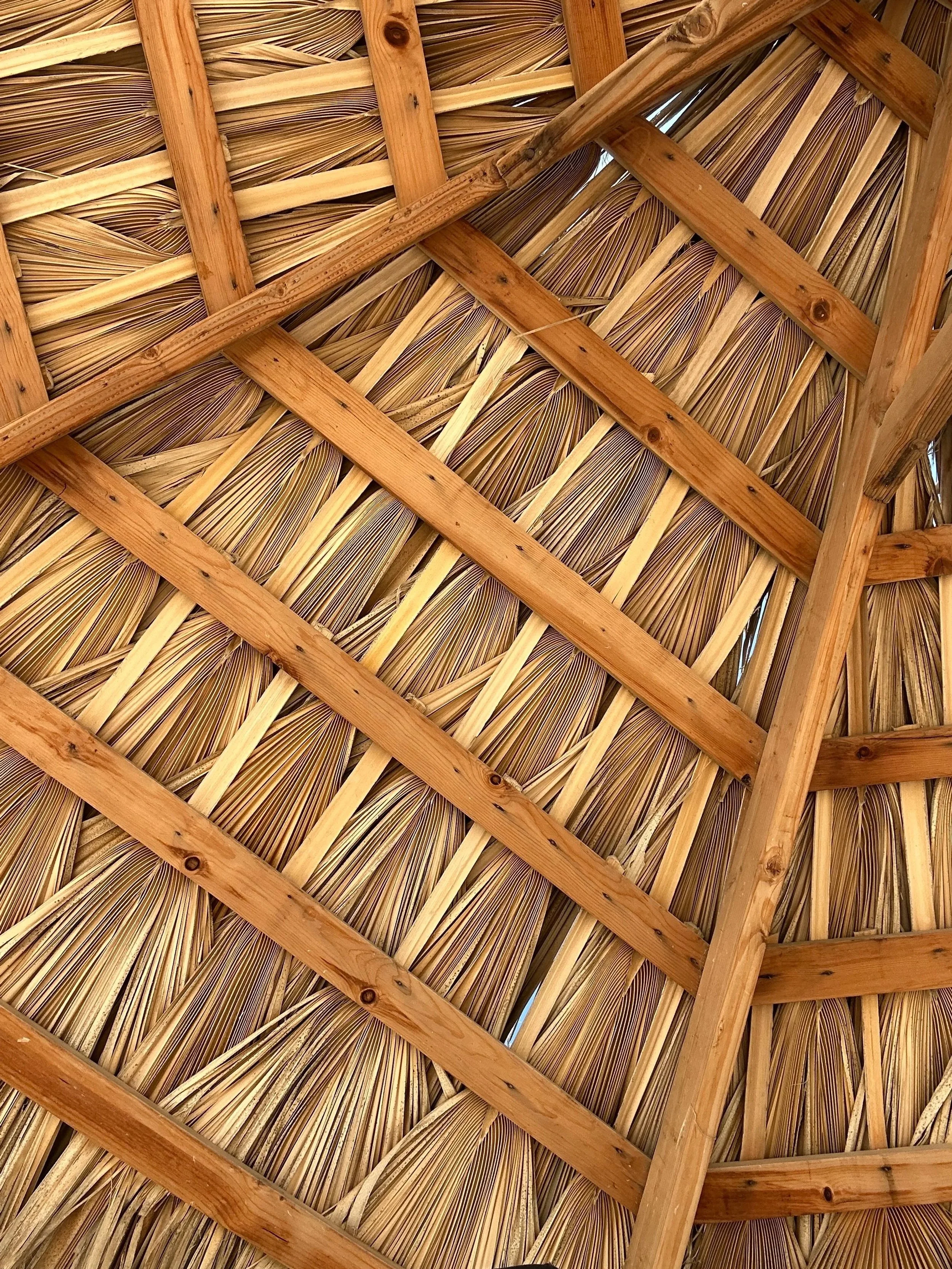 Close-up detail of traditional thatched roof structure with woven straw roofing and wooden beams, reflecting rustic Baja-inspired coastal architecture and natural materials used in SANTO design aesthetic in San Felipe