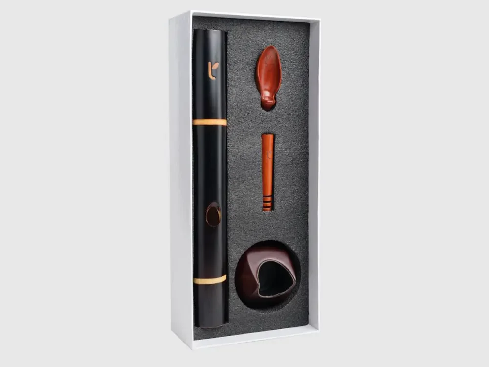A gift box containing a black and brown telescope, a brown leather eyepatch, an orange and brown wooden stylus, and a brown ceramic bowl.