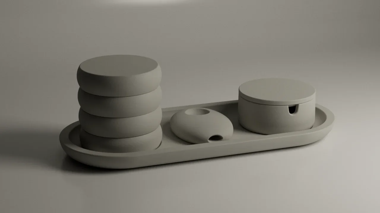 A minimalist, monochromatic set of ceramic containers and dishes on a tray, including stacked round boxes, a small oval dish, and a round box with a lid.