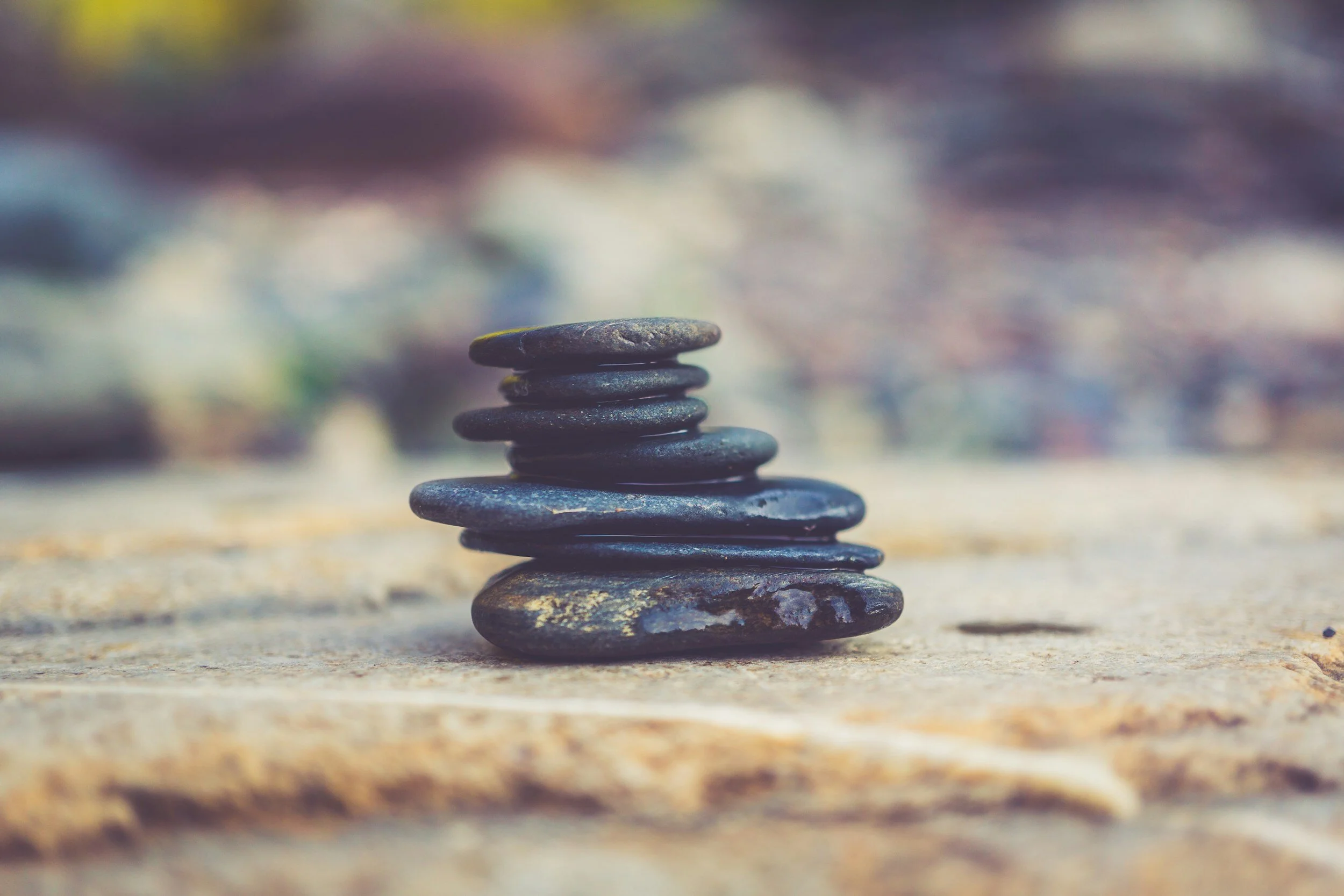Stack of smooth black stones arranged on a flat surface with a blurred natural background.