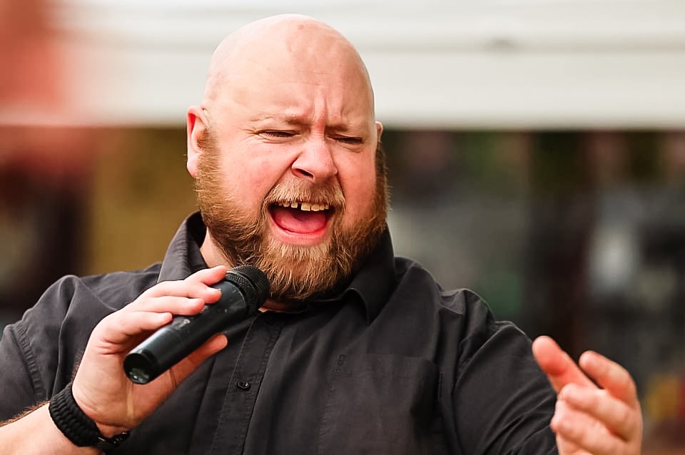 Bearded man singing with a microphone