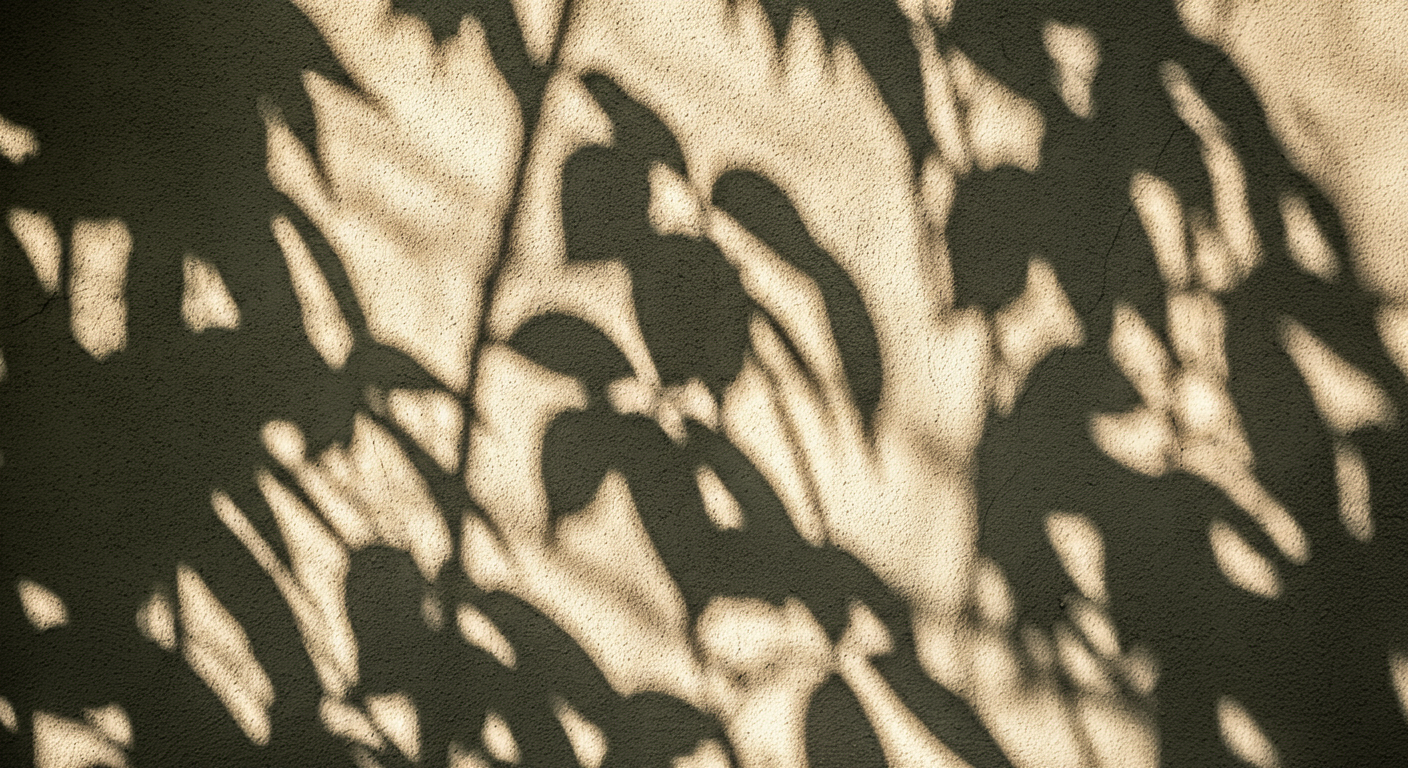 Shadows of plant leaves cast on textured beige wall.