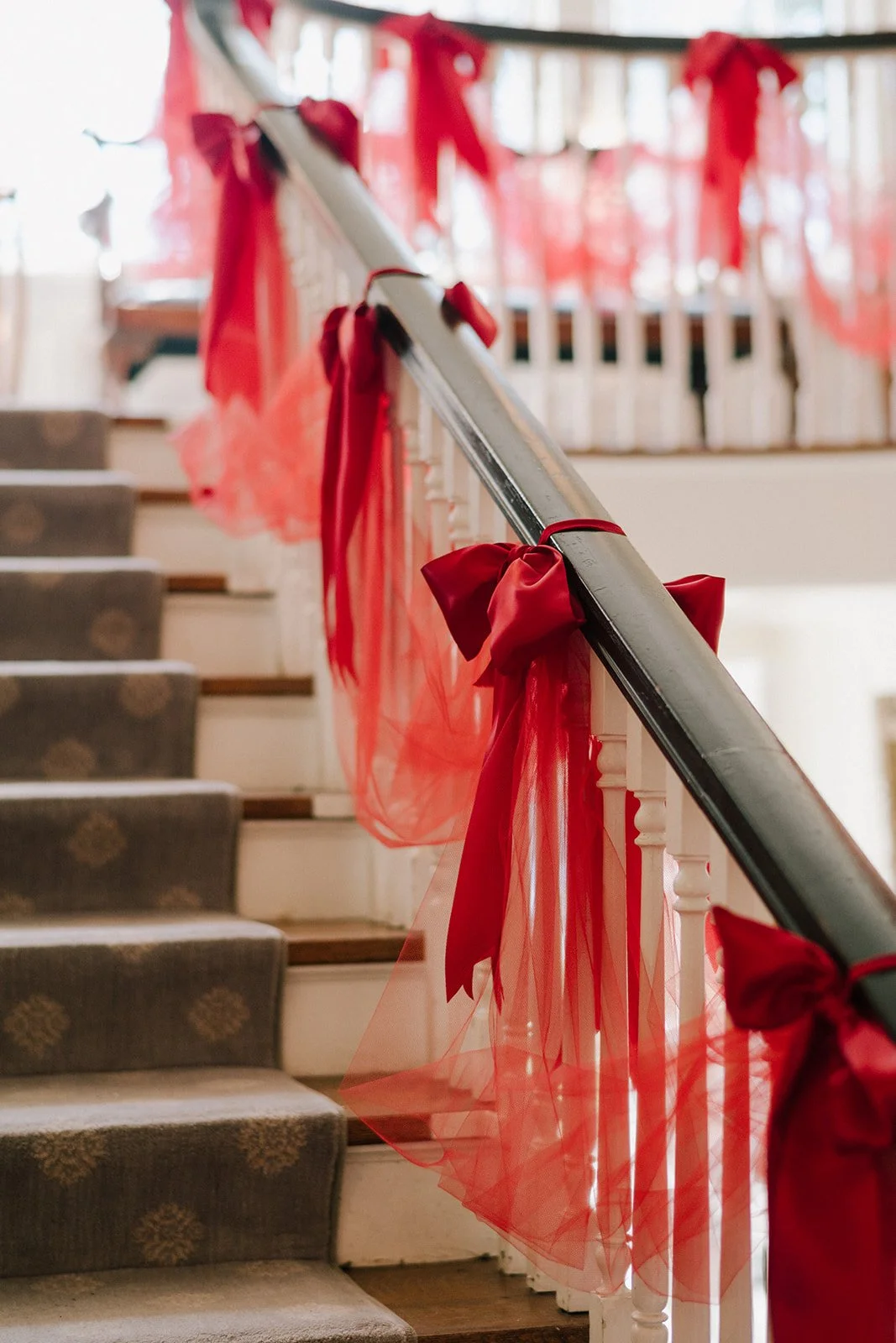 Decorated staircase with red ribbons and sheer fabric for a celebration or wedding event.