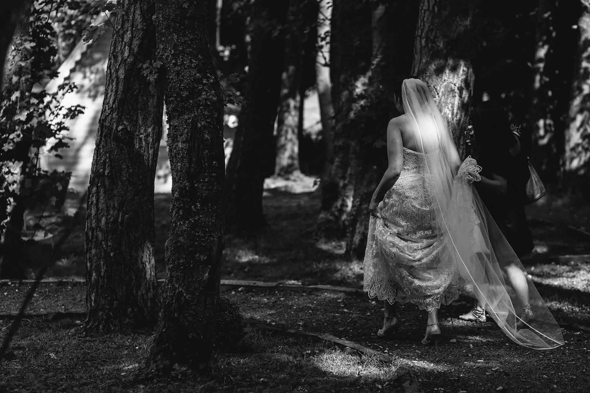 The bride walking through woodland at Woodhill Hall on the way to her first look with her husband to be.
