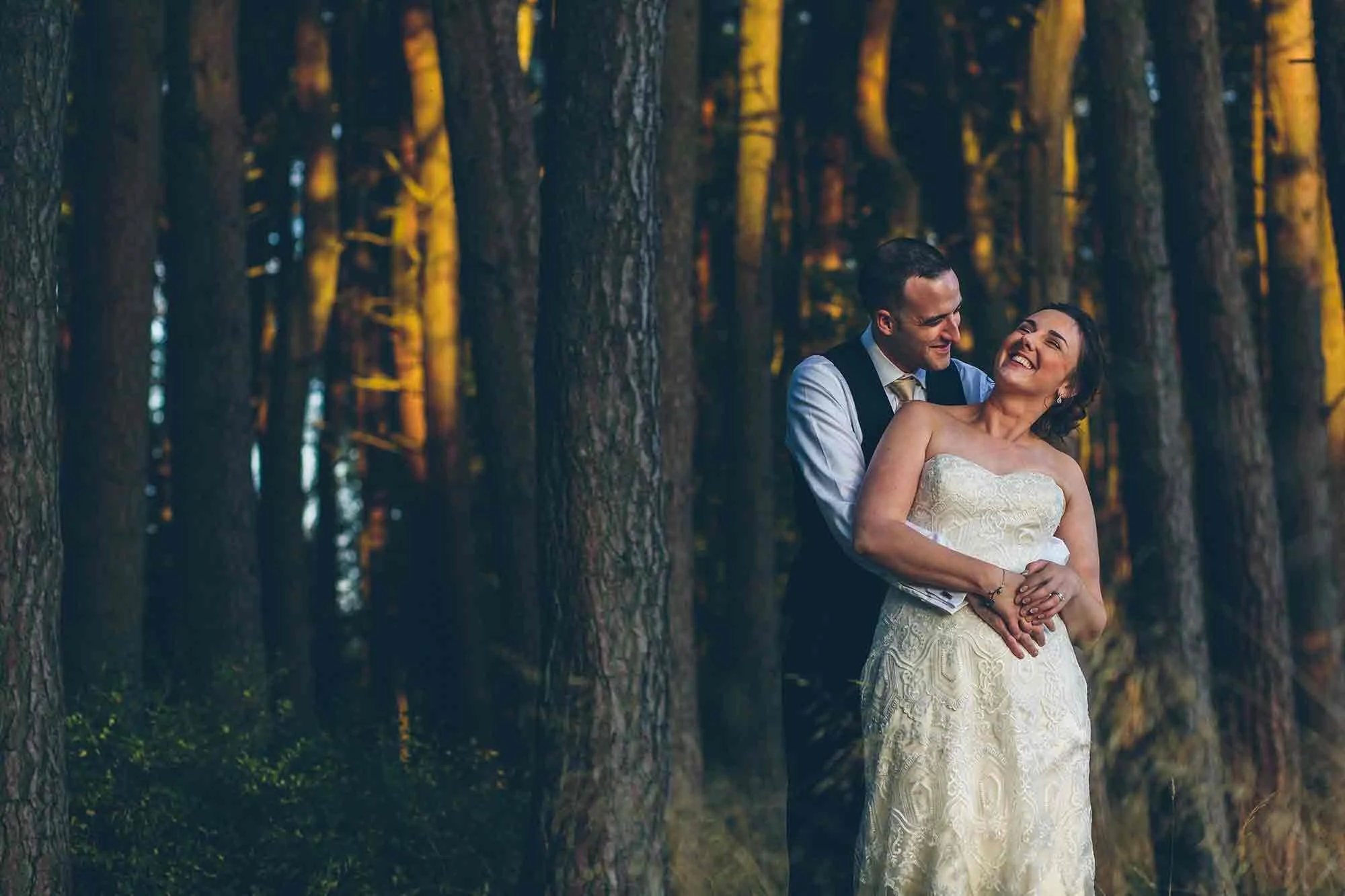 A portrait of the bride and groom in woodland at sunset during their Woodhill Hall wedding.
