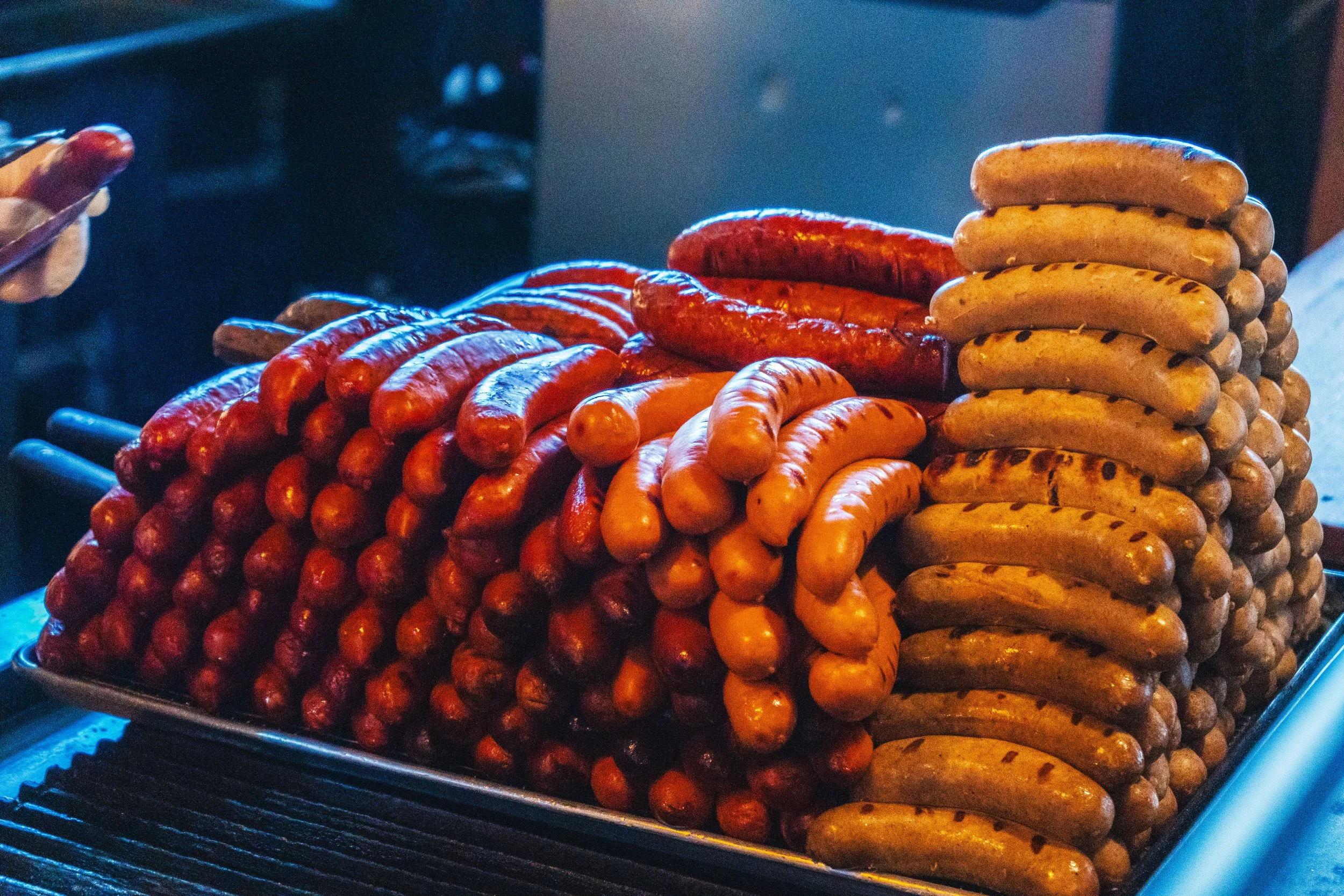 Assorted grilled sausages stacked on a tray.