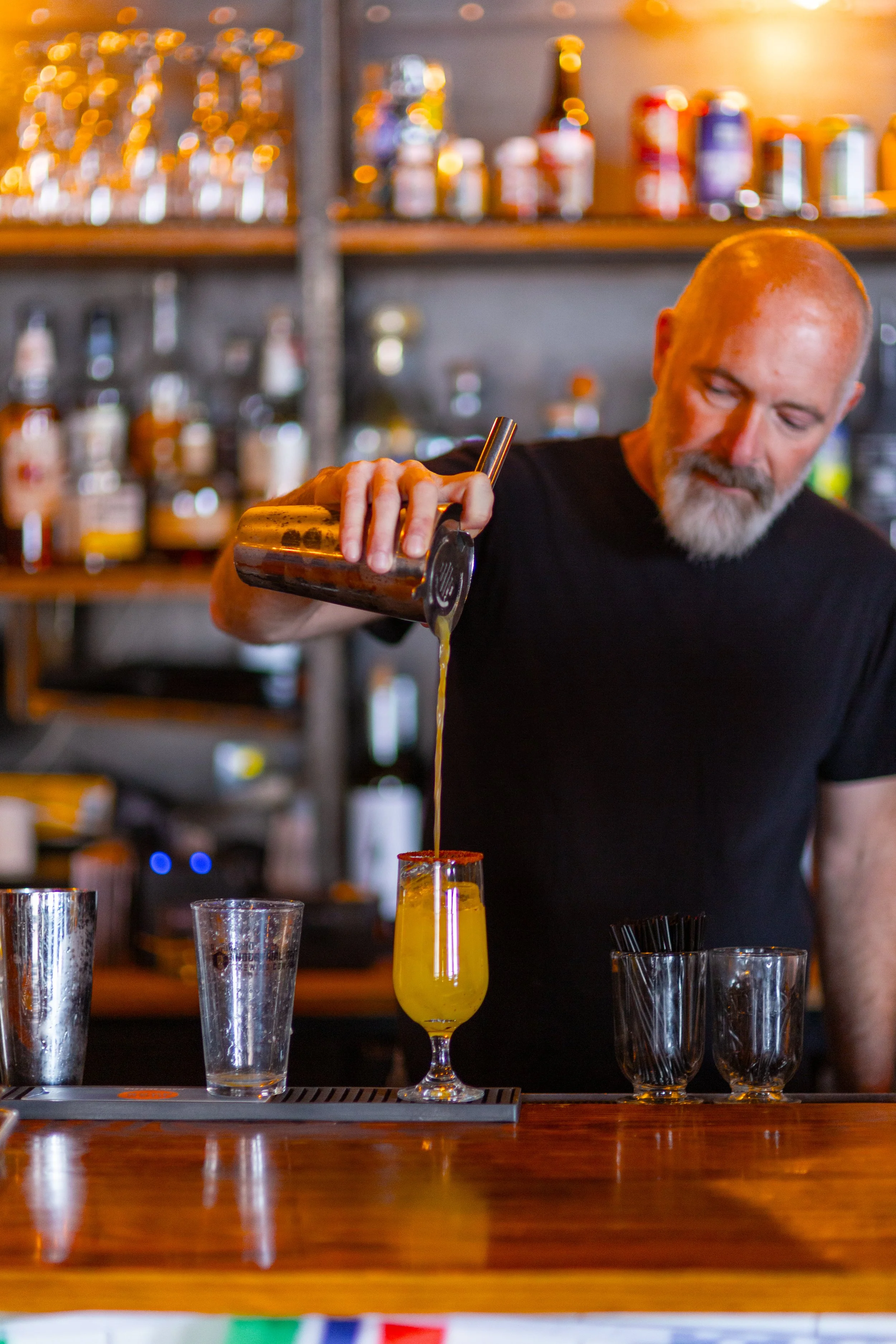 Bartender pouring drink from shaker into glass on a bar counter