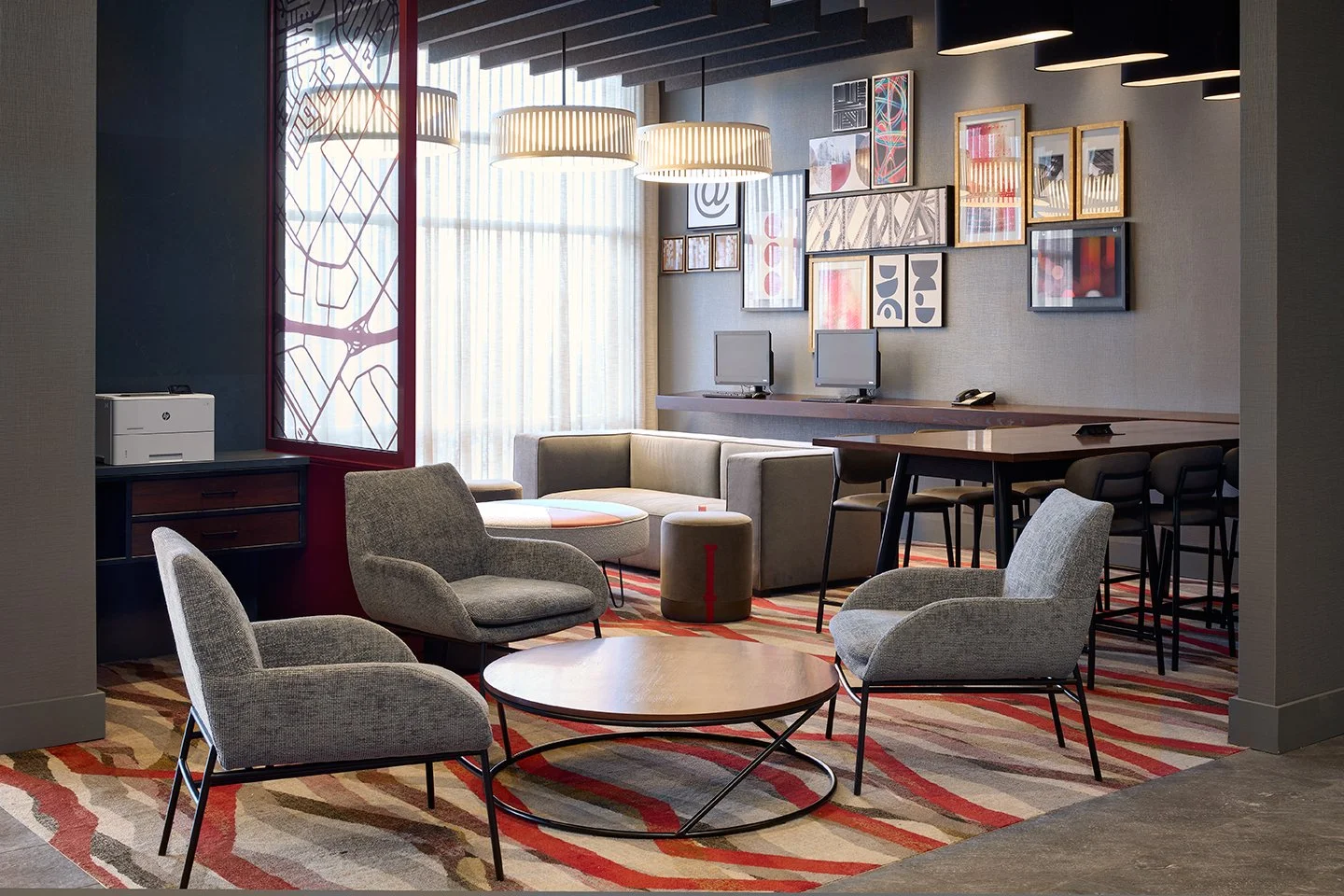 Red and grey hotel lobby with fabric seating, red decorative screen and gallery wall art
