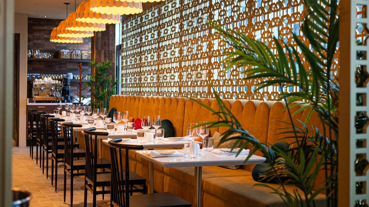 Warm wood restaurant interior with large yellow scalloped banquette, lattice screen and overhead lantern lights