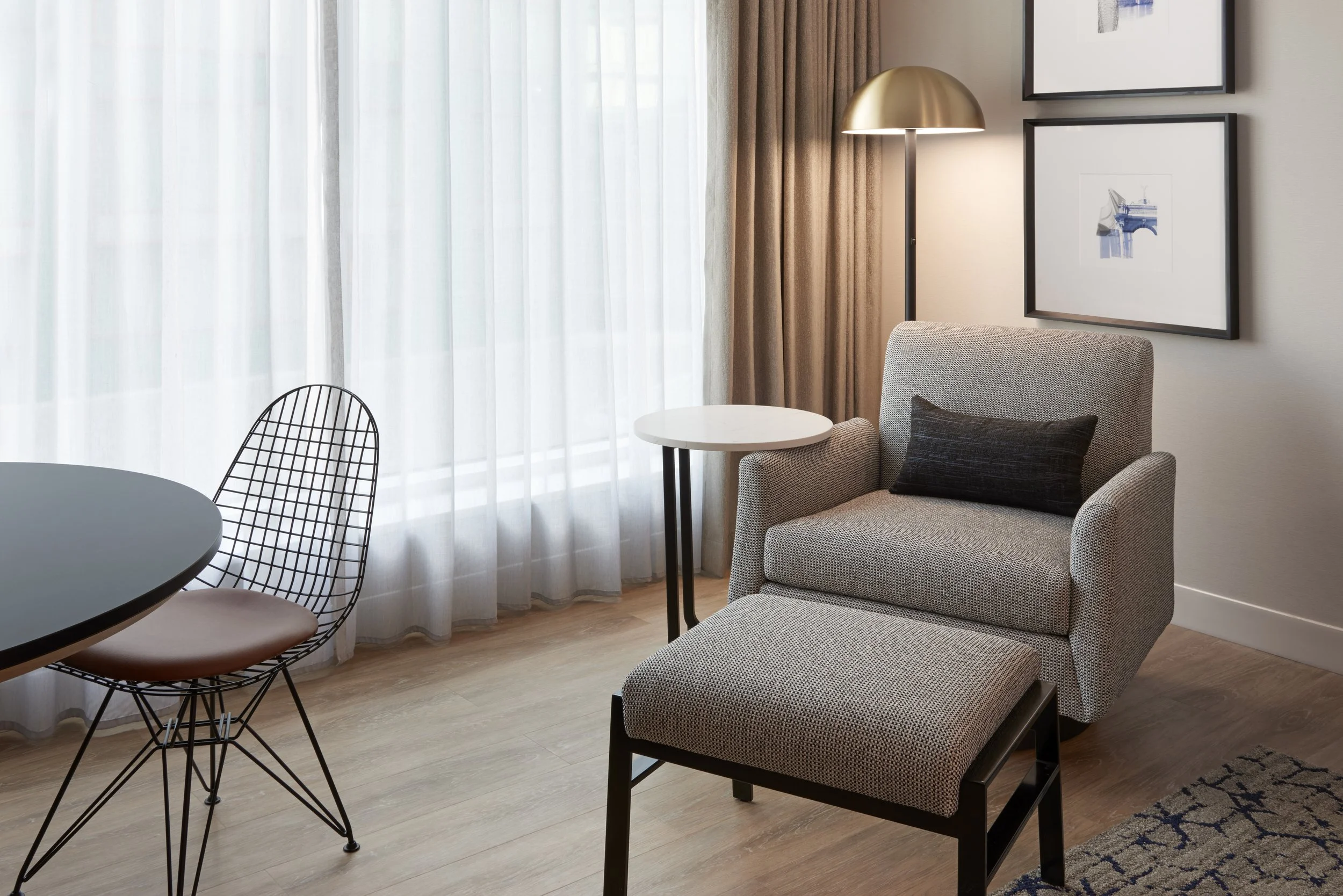 Hotel guestroom lounge chair and ottoman with lamp and artwork by window